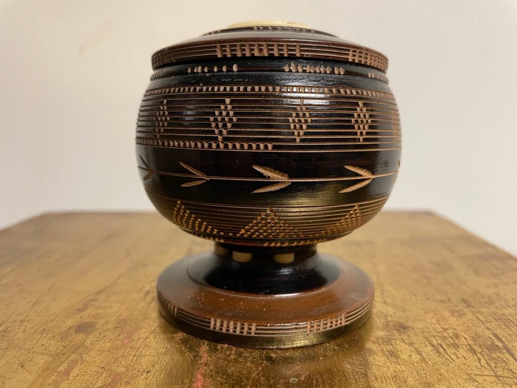 Caja redonda antigua de hueso y madera ebonizada, fabricada por balleneros, hacia 1850. Con medallón de hueso calado y soportes decorativos en espiral de hueso delicadamente tallados en la base. Diseños geométricos grabados en la superficie