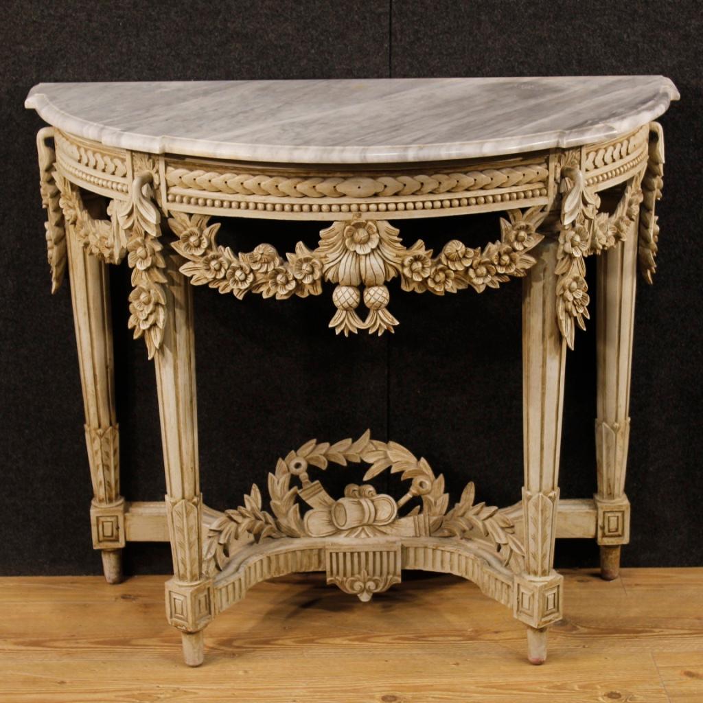 French console from 20th century. Furniture in richly carved and painted wood in Louis XVI style of excellent quality. Console table supported by four legs carved and adorned with floral ornaments of great pleasure. Top in original marble of good