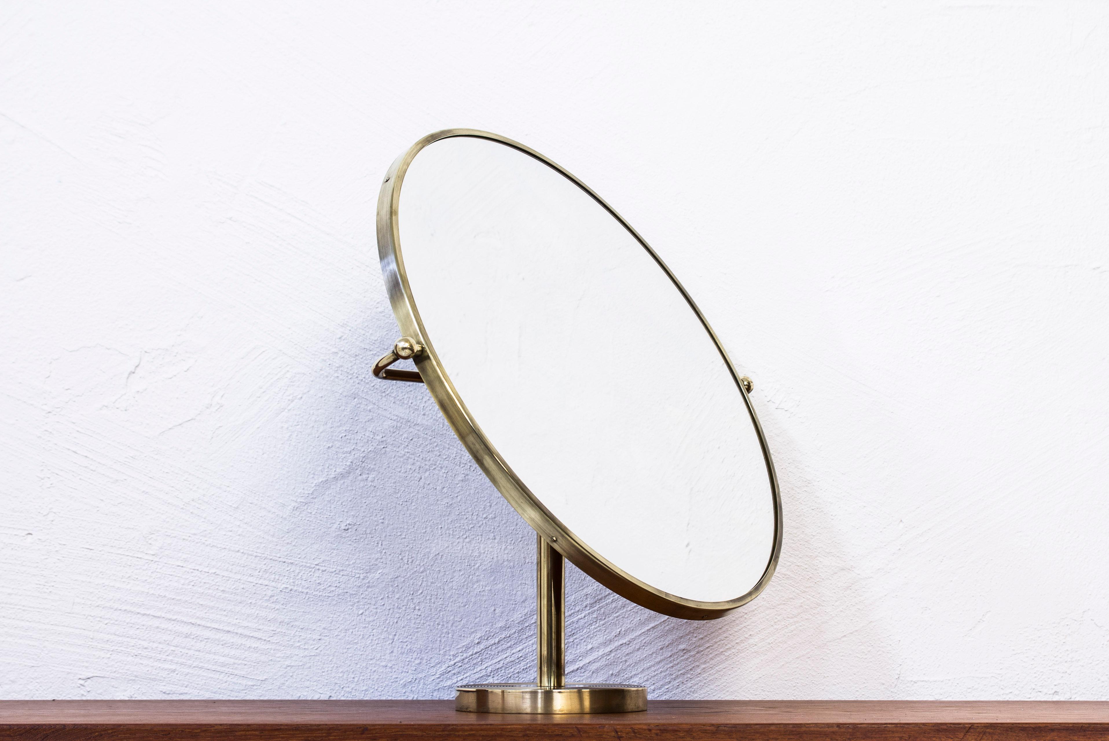 Vanity mirror model no 2214 designed by Josef Frank. Produced in Sweden by Firma Svenskt Tenn. Designed in 1934, this example, circa 1940s-1950s. Made from solid brass with mahogny wooden back part. Adjustable in angle. Very good condition with
