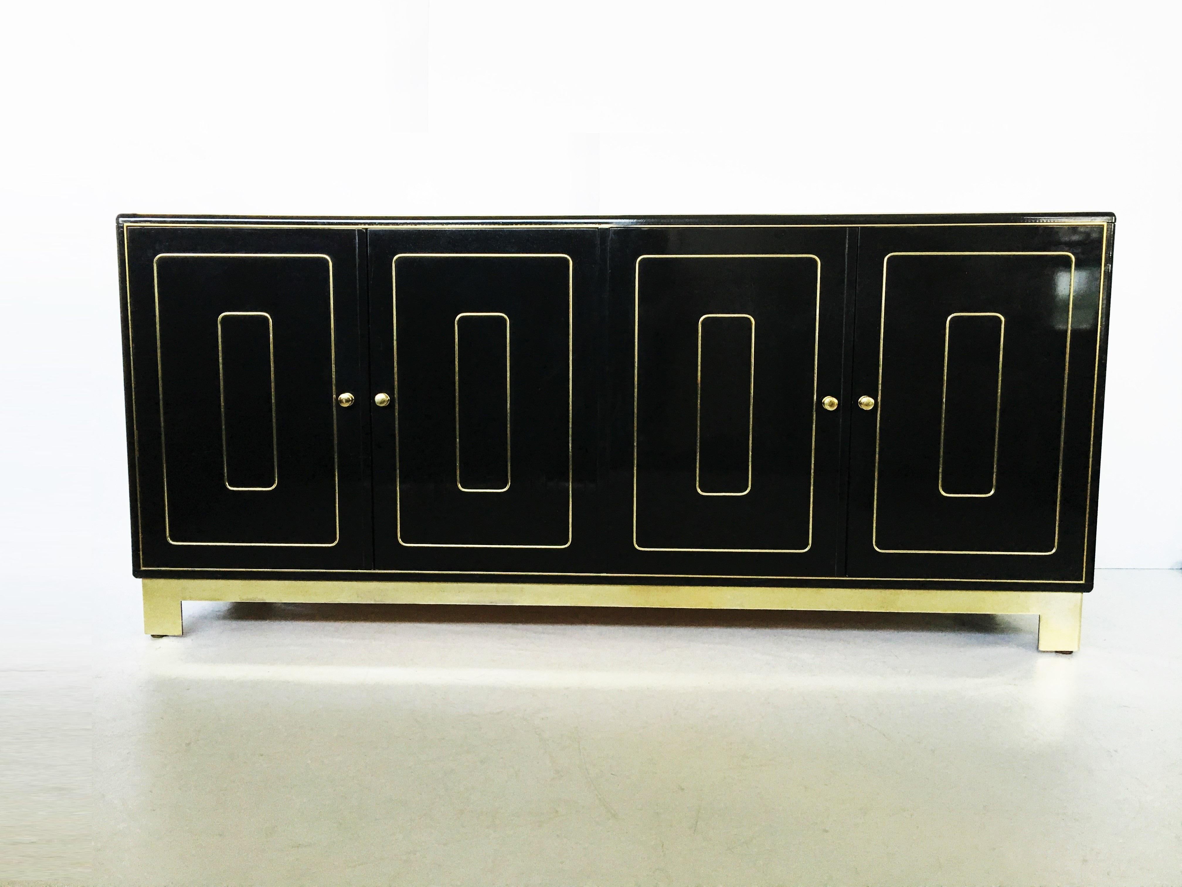 This beautiful four-door credenza in black lacquer with graphic brass inlays on doors and brass base by Romweber, American, 1970s. Featuring each pair of touch-latch doors open with simple brass peg pulls to reveal three solid wood drawers that pull