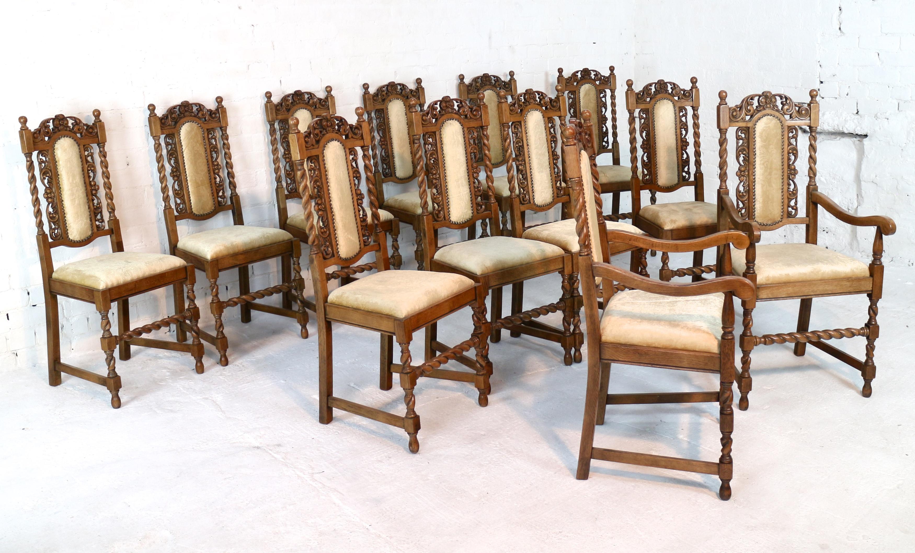 An attractive set of twelve Jacobean revival oak high back dining chairs comprising two carver armchairs and 10 side chairs. The padded backs surrounded by pierced carved fruit and foliage with ball finials and barley twist uprights, front legs and