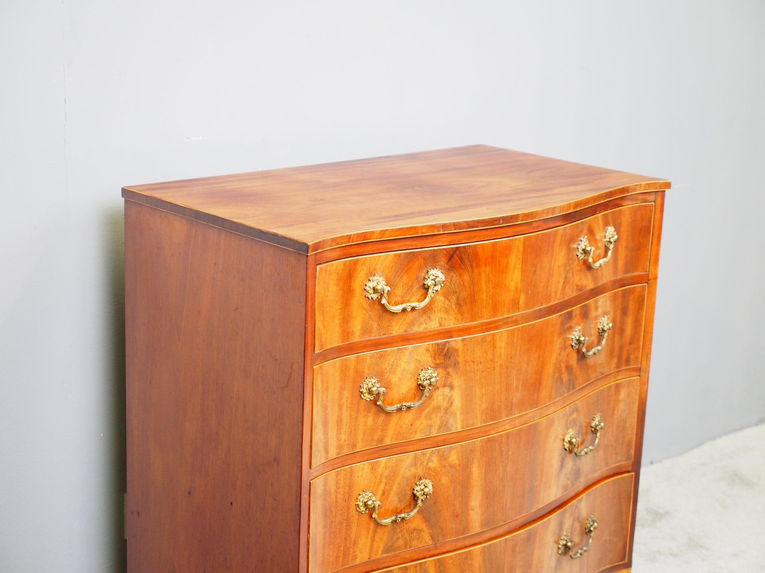 Hepplewhite style, inlaid mahogany, serpentine fronted chest of drawers, circa 1850. The shaped top in figured mahogany has a boxwood inlaid cross-banded fore-edge and is over four inlaid, graduated drawers. These are in flame mahogany and all have