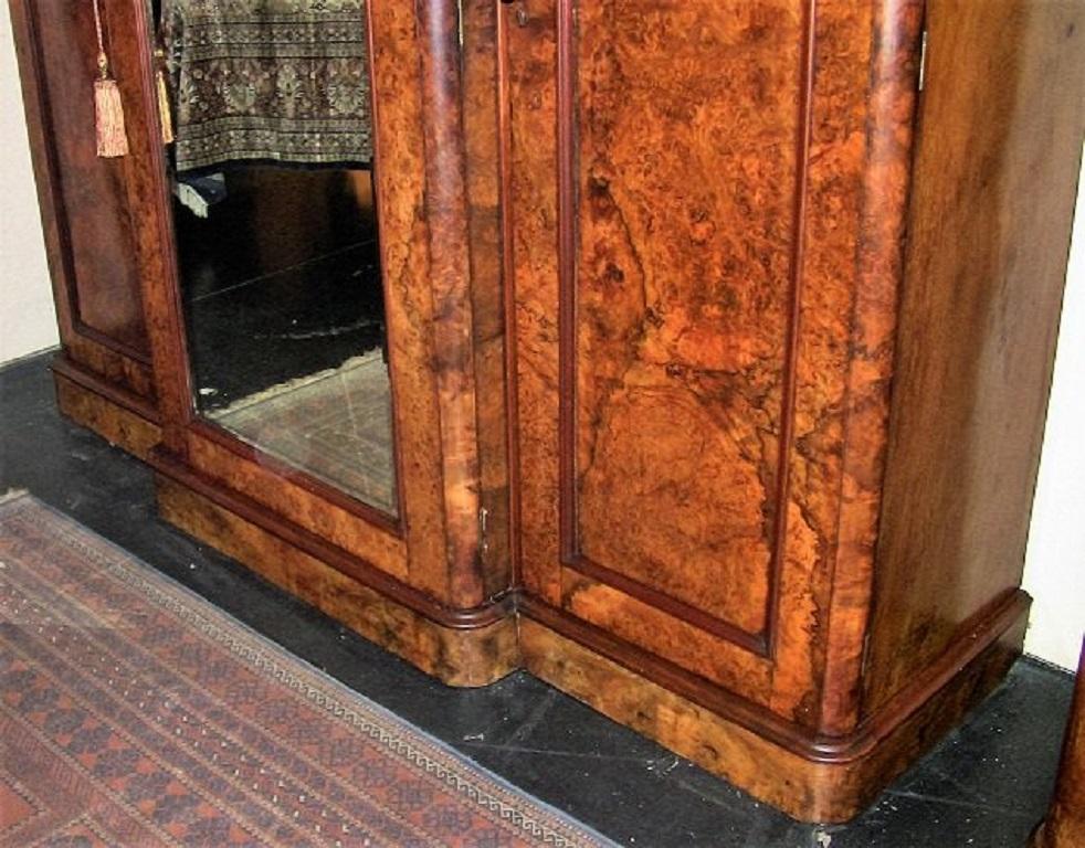 This is a late 19th century circa 1870, burl walnut breakfront wardrobe.

It has three doors, the two side doors open to reveal space for the hanging of clothes etc.

One side (right) has a secret drawer at the base.

The center breakfront