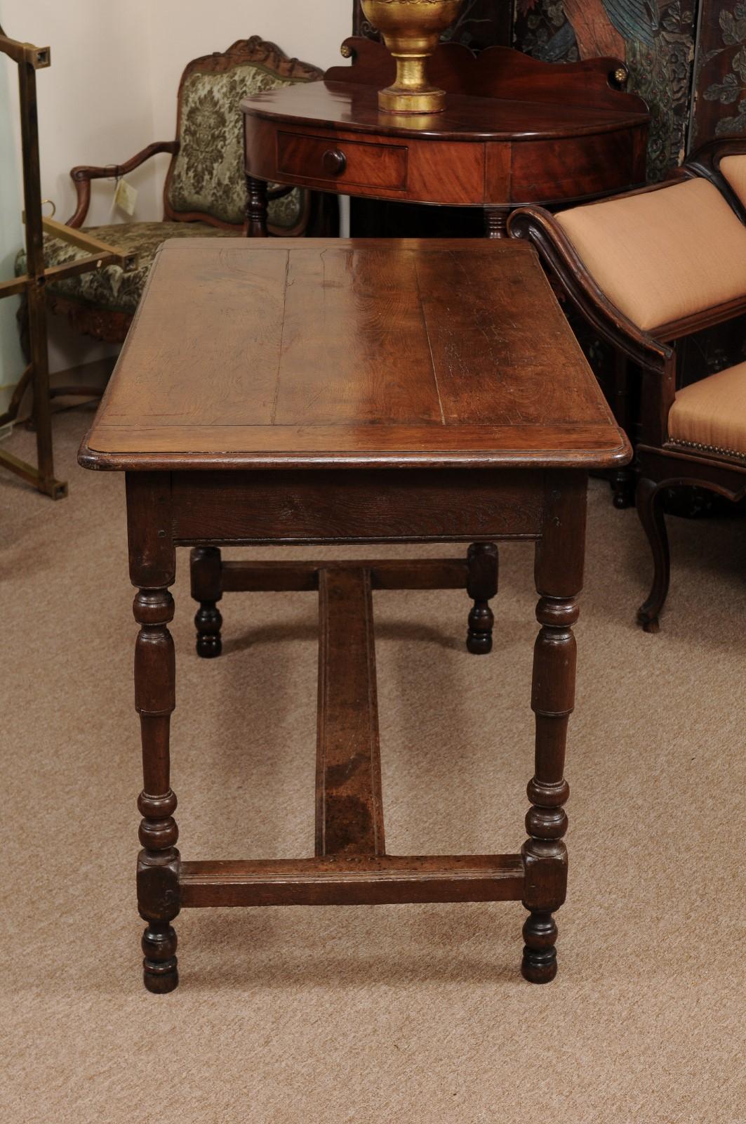 The 19th century English oak writing table with one-drawer, turned legs and stretcher.