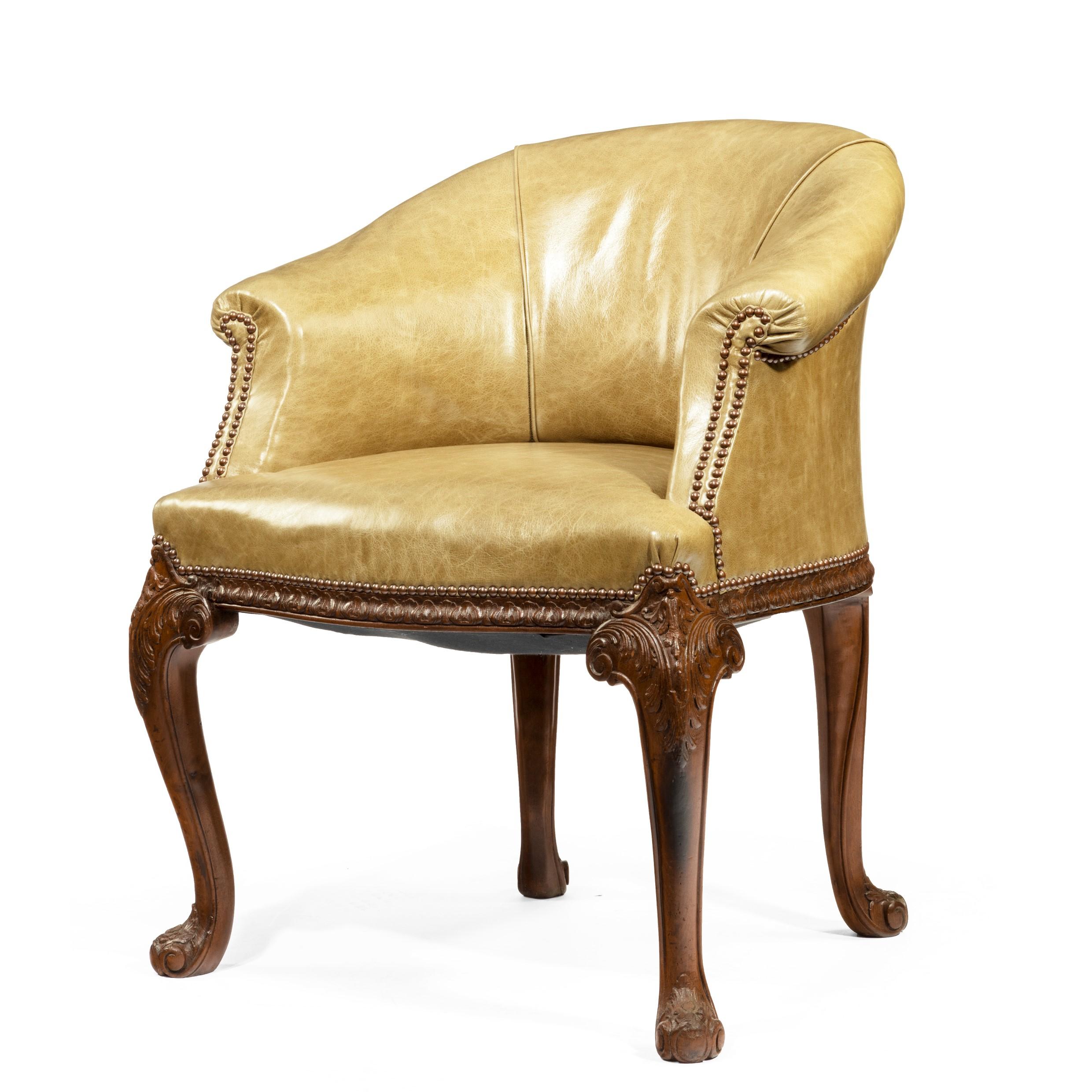 A late Victorian mahogany tub desk chair in the Chippendale style, the fully upholstered shaped back curving down to scrolling arms, with acanthus leaves carved along the seat rail and on the cabriole front legs, English, circa 1900.
