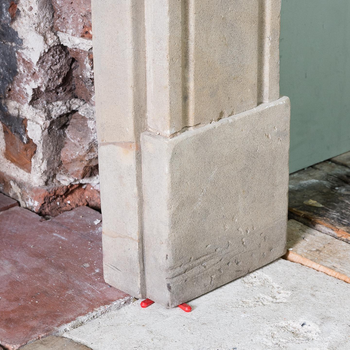 A Regency Ancaster stone chimneypiece, early 19th century, the rectangular shelf above frieze centred by plain tablet, the channel moulded jambs surmounted by rounded endblocks, repaired break to shelf. Aperture width 97.5cm x 93.5cm high.

In good