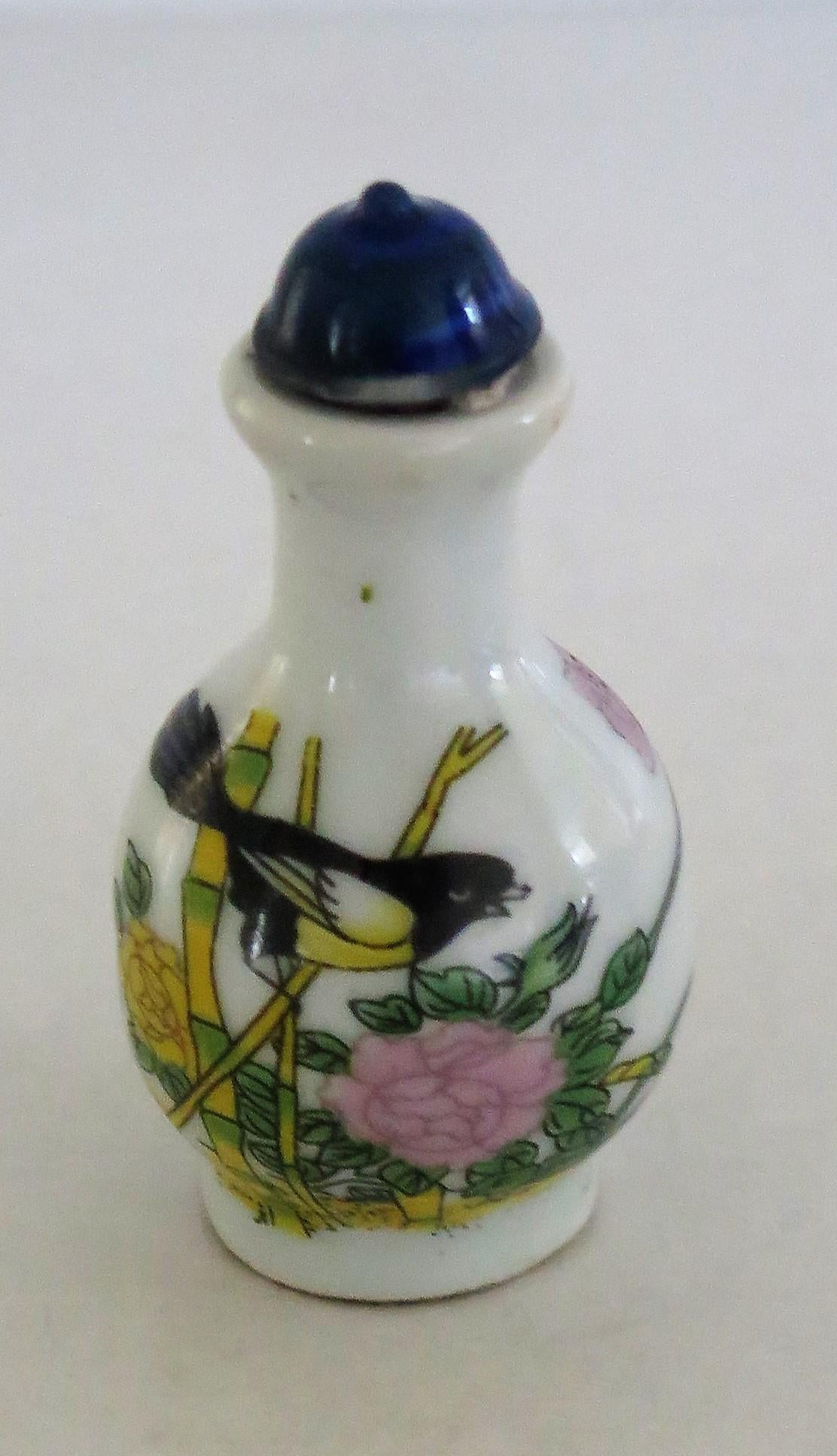 This is a good quality, hand-painted, Chinese Snuff Bottle made from porcelain, circa 1930. 

The bottle is well potted and has a footed baluster shape leading to a narrow neck, with a matching cone shaped stopper. 

The main decoration depicts