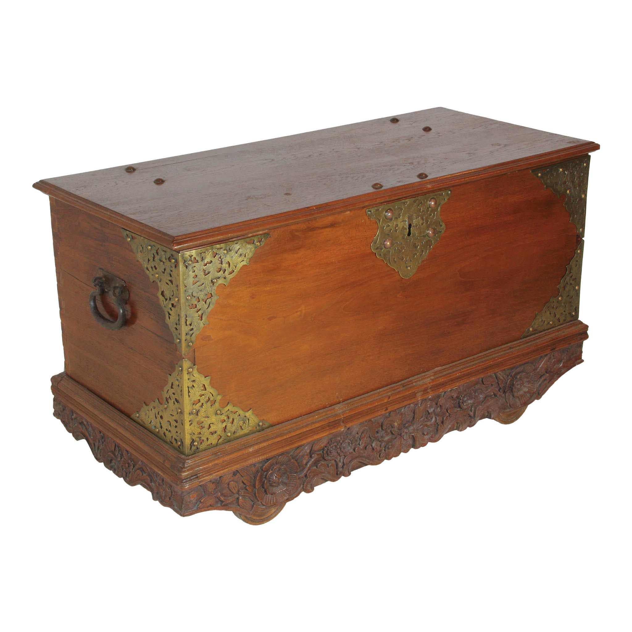 Beautiful hardwood trunk with decorative brass corners and key plate. Lovely carved floral and foliage trim adorns a bottom apron around the base of the trunk. Four iron wheels beneath the trunk make it easier to transport.
