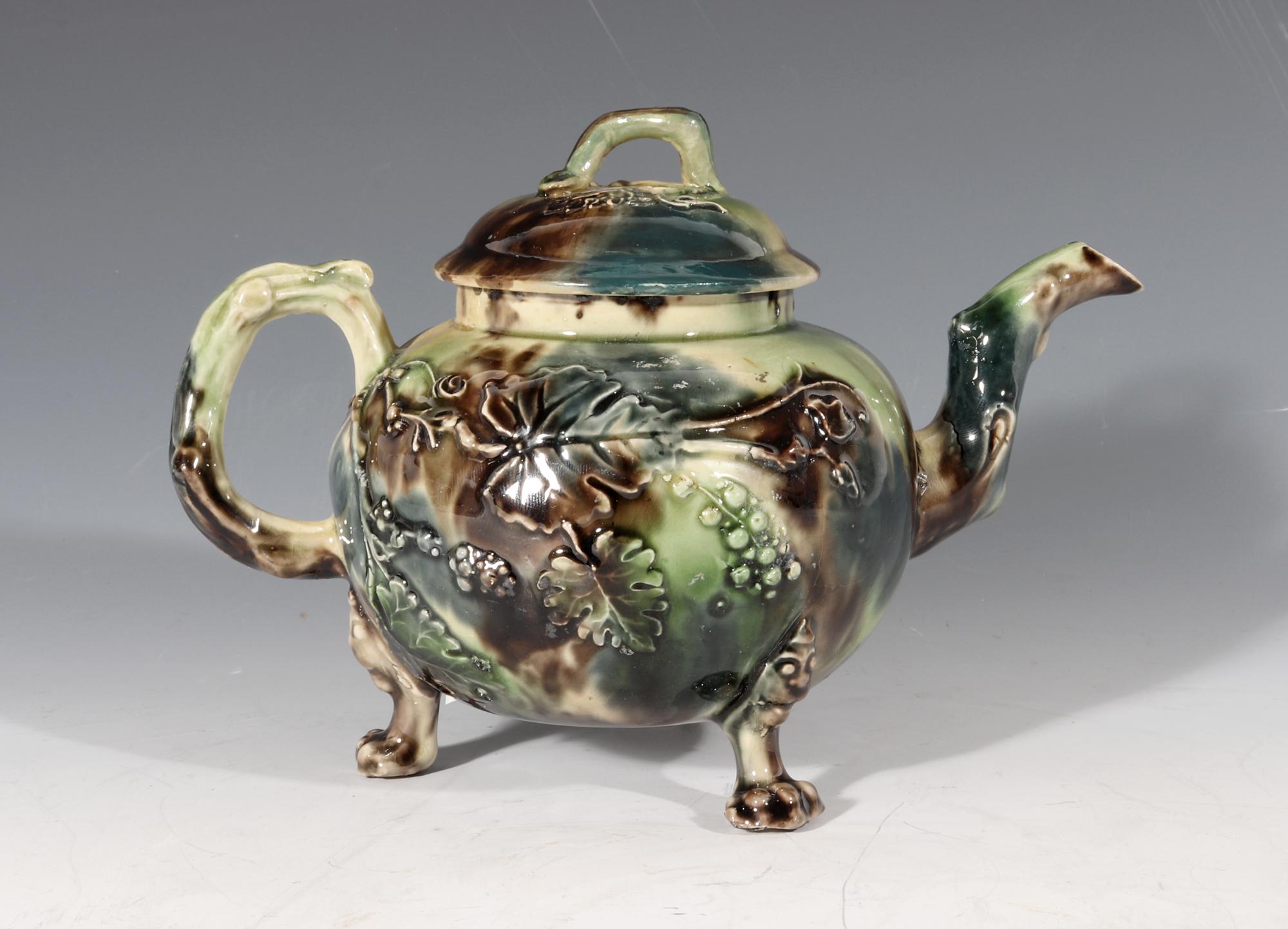 Staffordshire Whieldon-type creamware teapot and cover,
circa 1765-1775

The Whieldon-type cream earthenware teapot has a moulded design of grape vines and large grape leaves to the front and back. The spout and handle of a crabstock form. The
