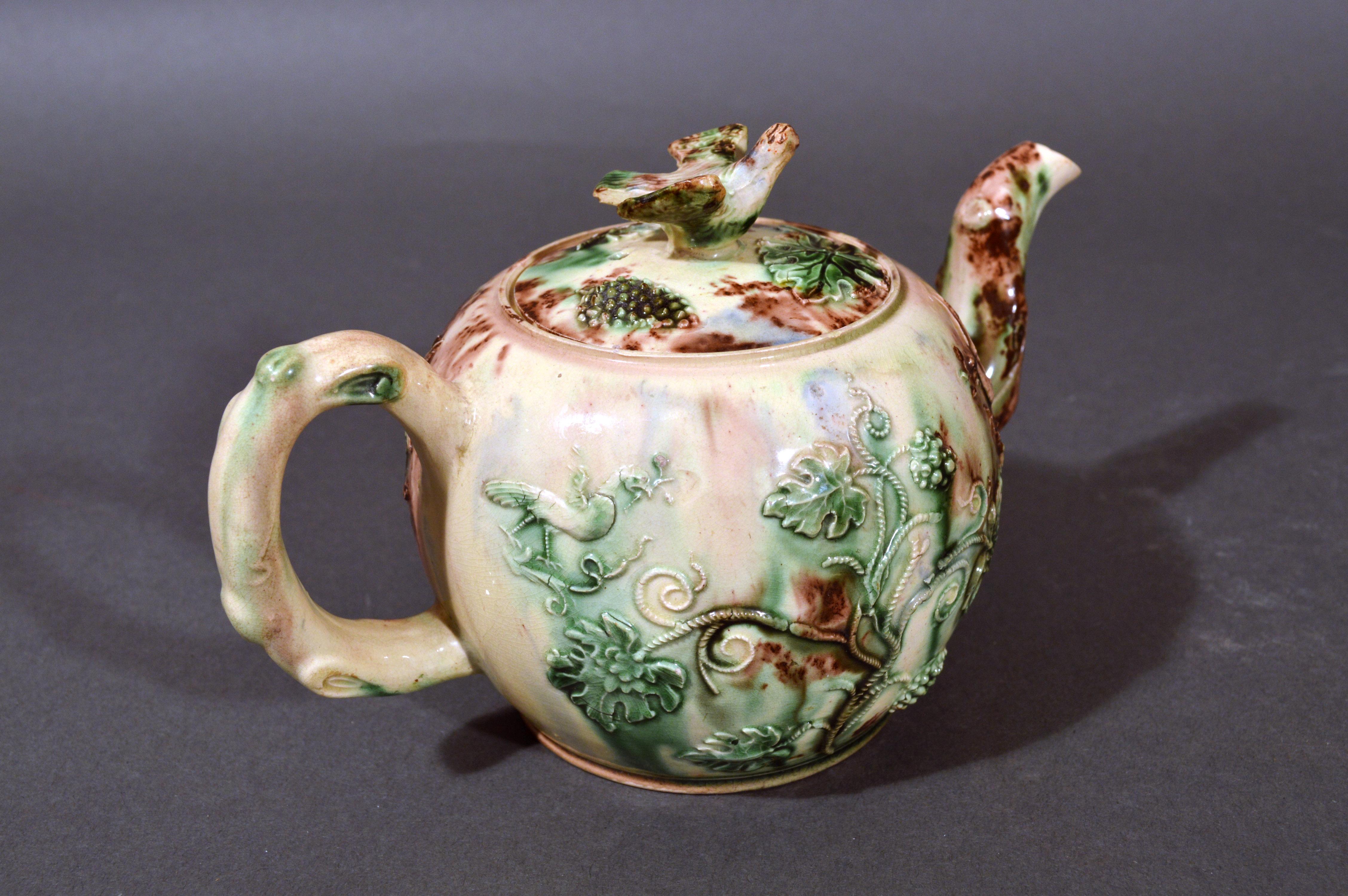 Whieldon-type creamware apple teapot and cover,
Staffordshire,
circa 1755-1765
   

The lead-glazed earthenware creamware teapot and cover is of globular form like an apple with an inset lid surmounted with a bird, its wings outstretched, as a