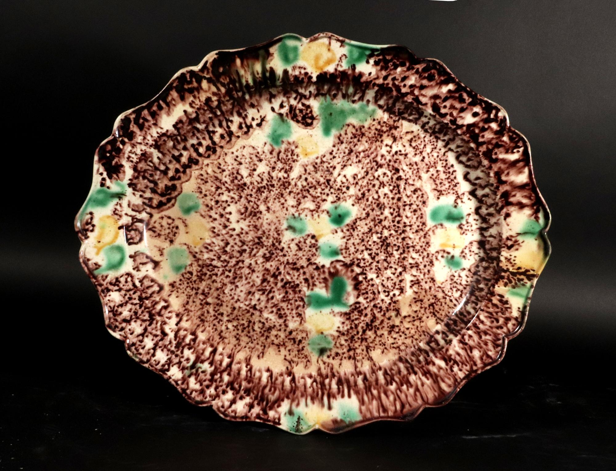 Whieldon-type Large Creamware Tortoiseshell Platter,
Circa 1765-75

The large Staffordshire creamware tortoiseshell-glazed platter, of Whieldon-type, is of a large oval silver shape with shaped wavy rim, splashed and sprinkled in manganese brown