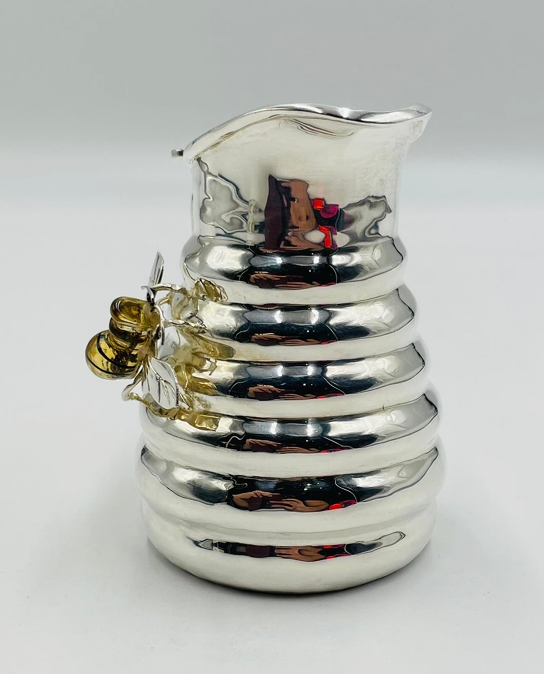 Una deliziosa brocca d'argento Los Castillo del 1960 che sembra uscita direttamente da un magico giardino di Taxco. Realizzata in ottone e riccamente argentata, questa piccola lattiera scultorea è avvolta da anelli simili a quelli di un alveare e