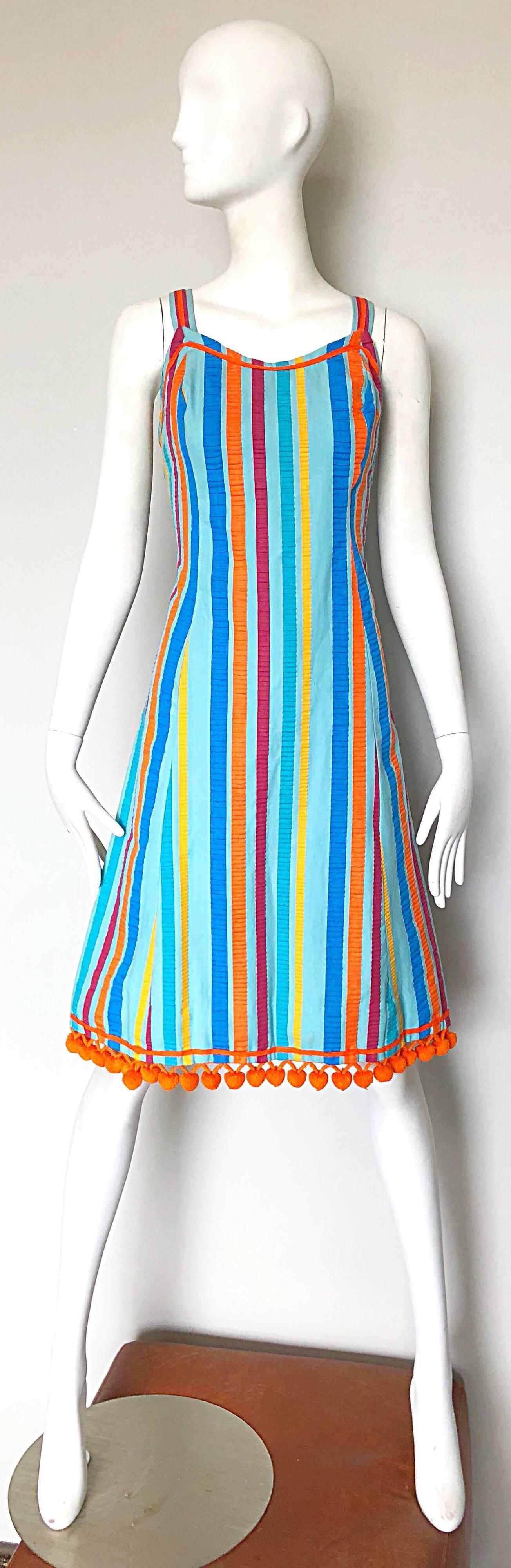 Whimsical and chic TOBY TANNER vintage 1960s colorful striped 'pom pom' cotton A-Line sleeveless dress! Features vibrant vertical stripes in blue, turquoise, raspberry pink, orange and yellow. Fluffy orange pom poms along the entire hem. 
Fitted