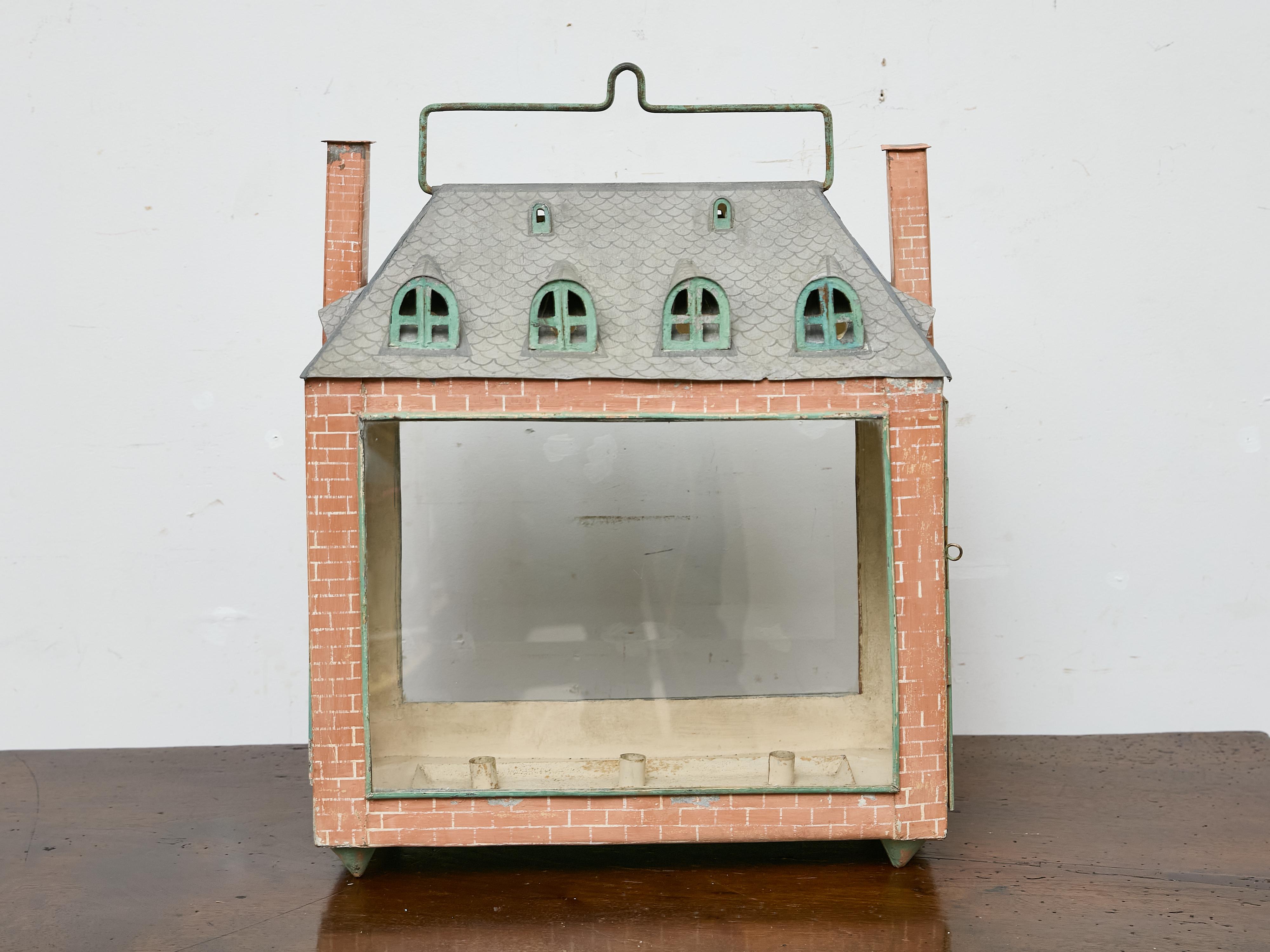 Rich in charm and imagination, this 19th-century English tôle candle lantern was crafted in the form of a miniature brick townhouse. Featuring hand-painted faux masonry, a pitched roof with dormer windows, and dual chimneys, it captures the