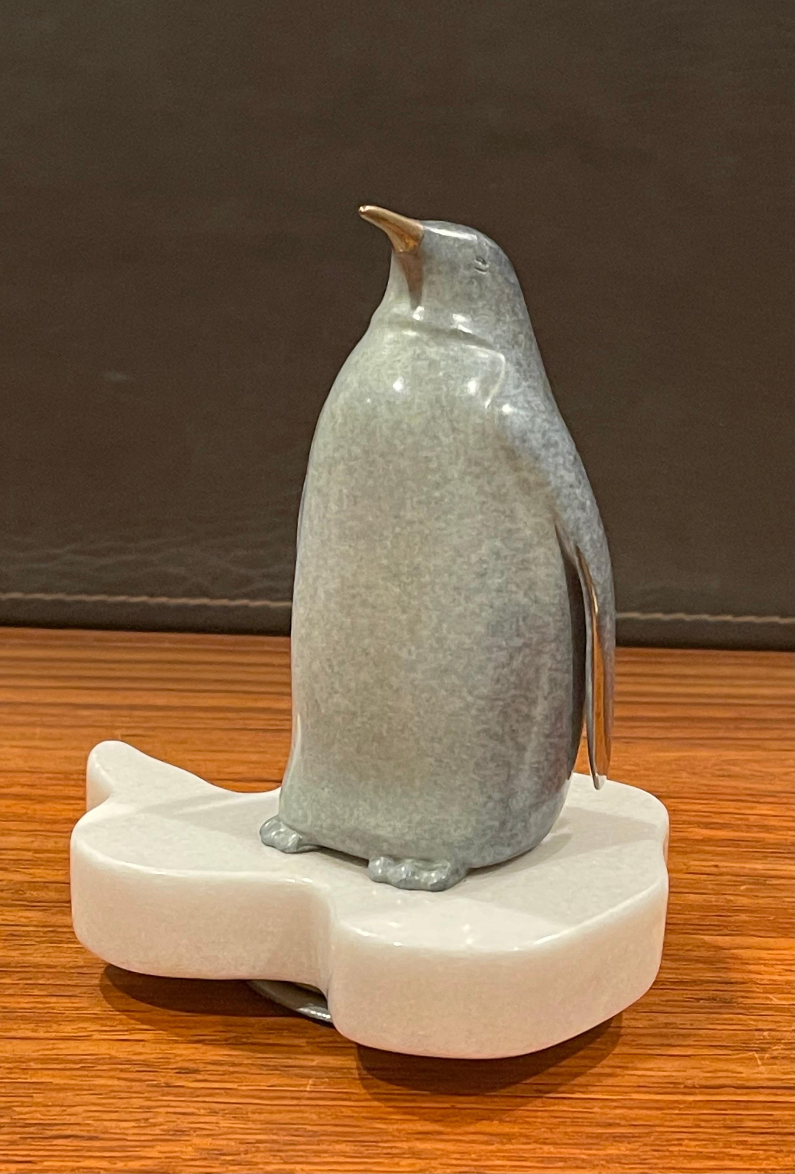 A very cool, unique and whimsical patinated bronze penguin sculpture on a rotating white marble base by noted wildlife sculptor Scott Hanson, circa 1999. The piece is in excellent condition and measures 6