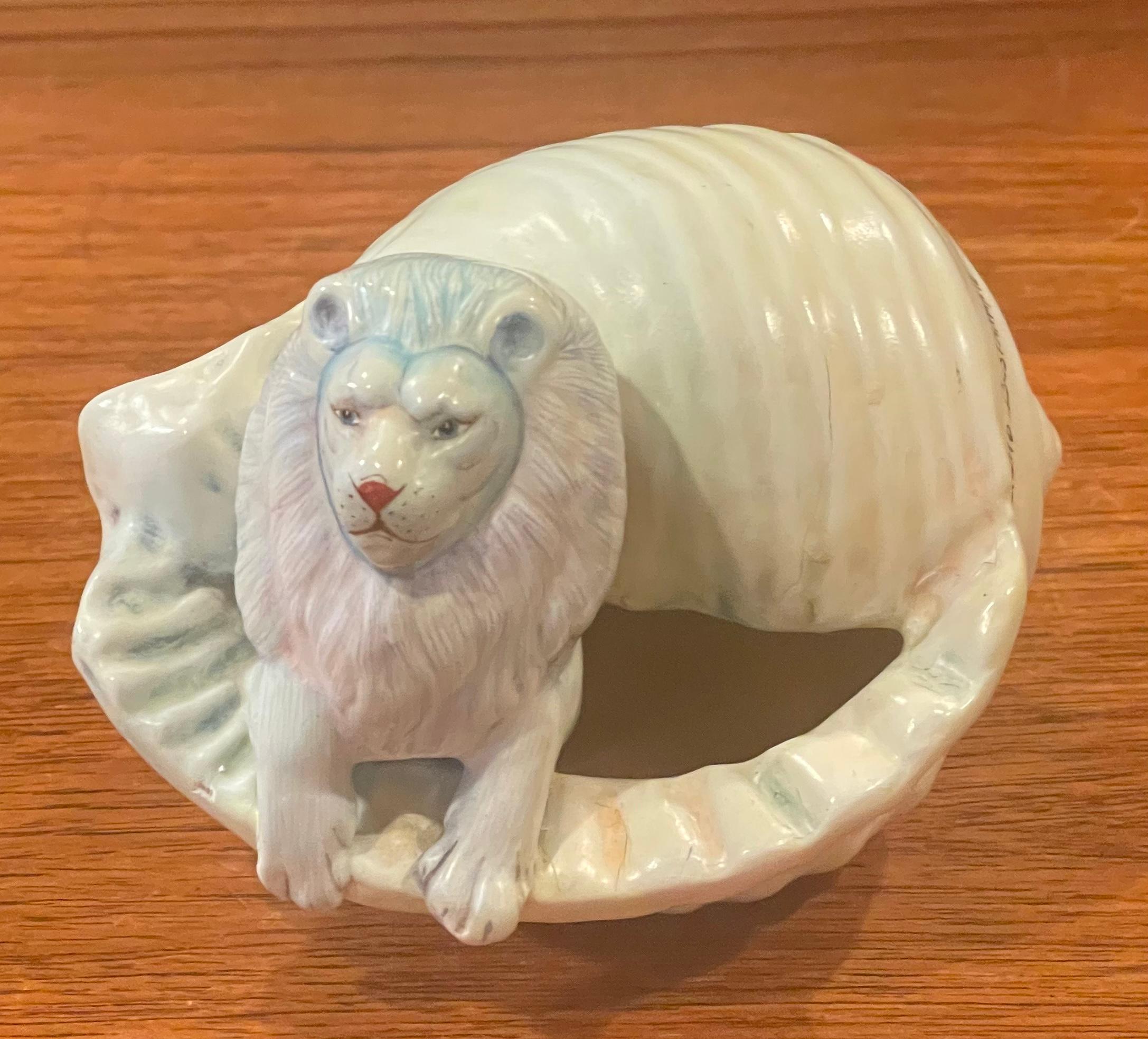 A very cool, unique and whimsical ceramic lion in conch shell sculpture by Mexican artist, Sergio Bustamante, circa 1995. The piece was acquired directly form the artist and is beautifully hand painted on ceramic; it measures 5