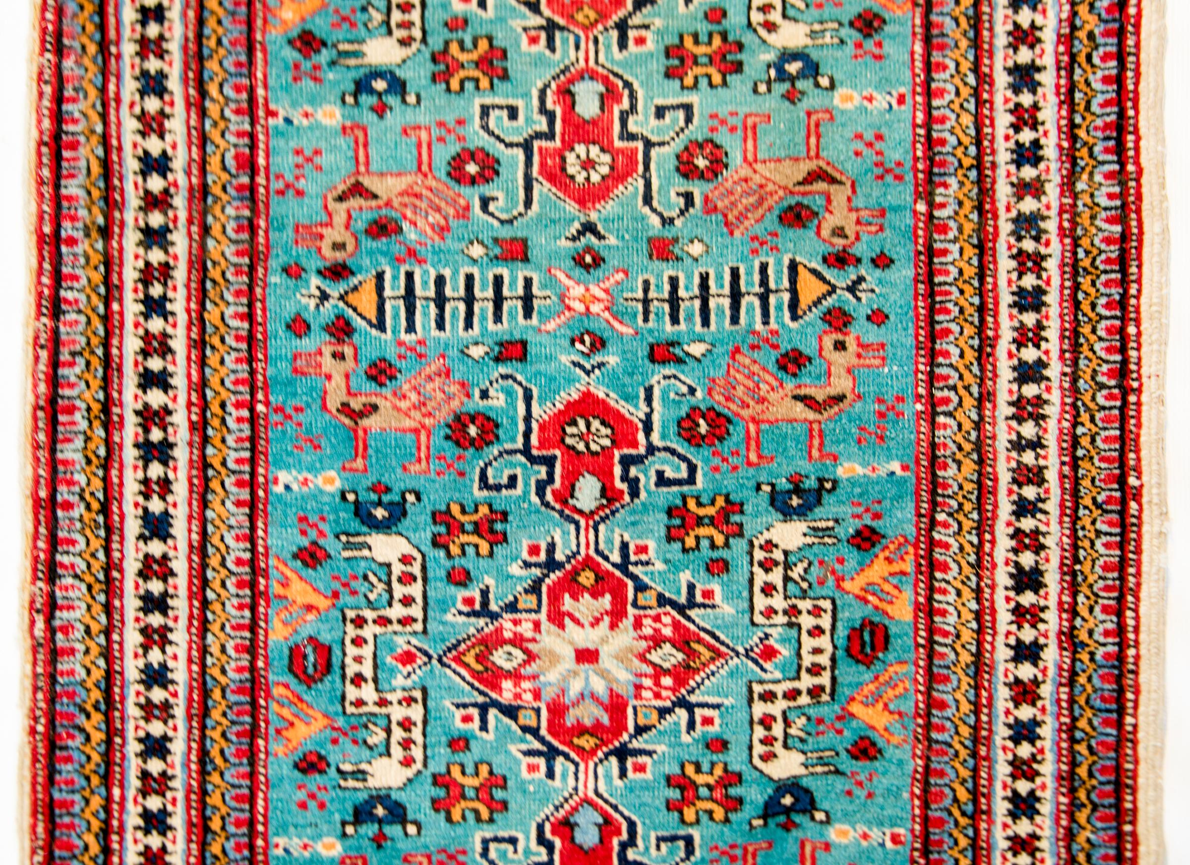 A lovely and whimsical early 20th century Russian Shirvan rug with a pattern containing large red diamond medallions on a turquoise ground amidst a field of birds, snakes, and stylized flowers. The border is complex with multiple stylized floral