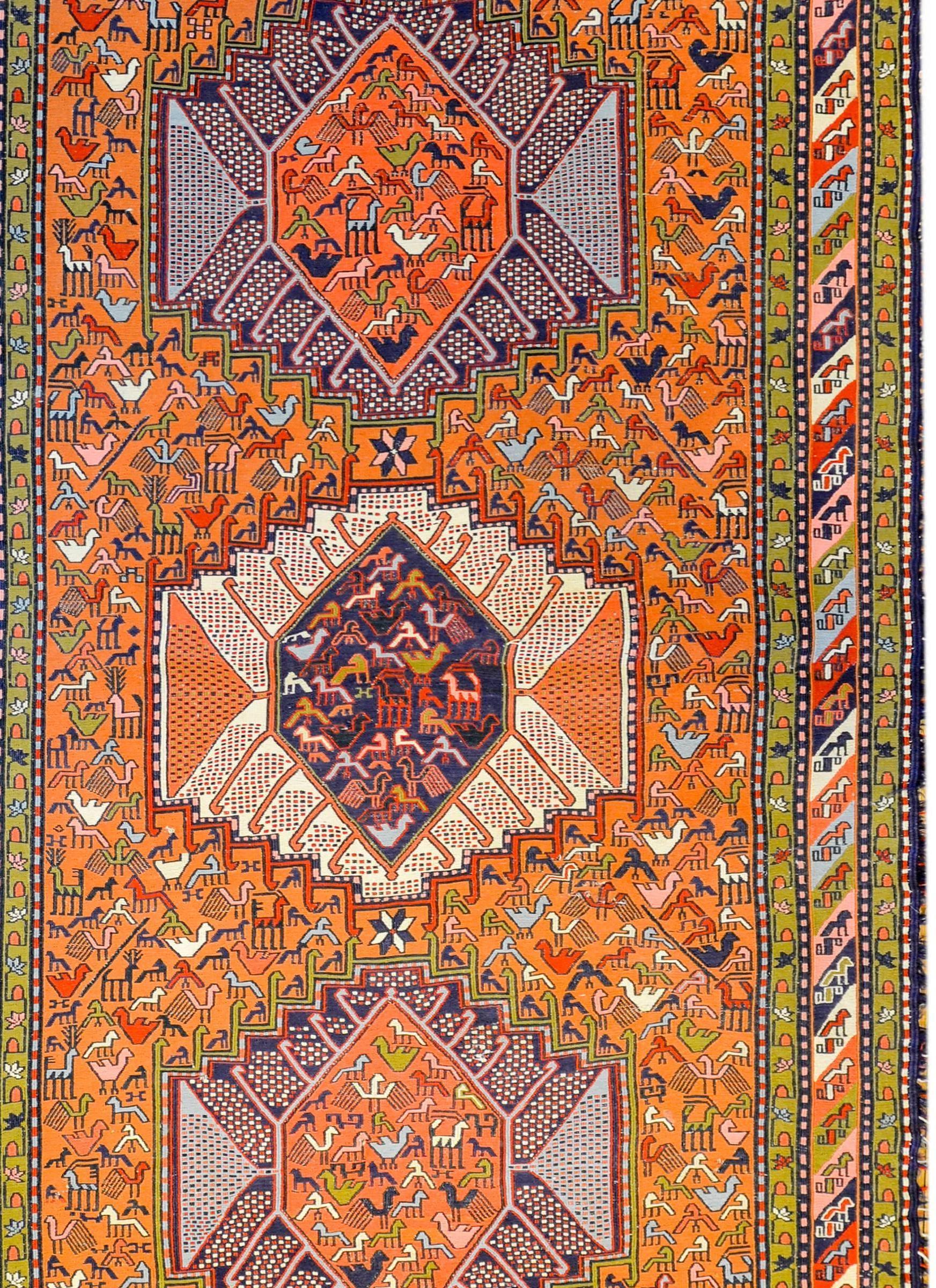 A wonderful early 20th century Persian Sumak rug with five large hexagonal medallions each filled with myriad birds, on a field of tightly woven myriad birds woven in crimson, green, and indigo, on a bright orange background, surrounded by a complex