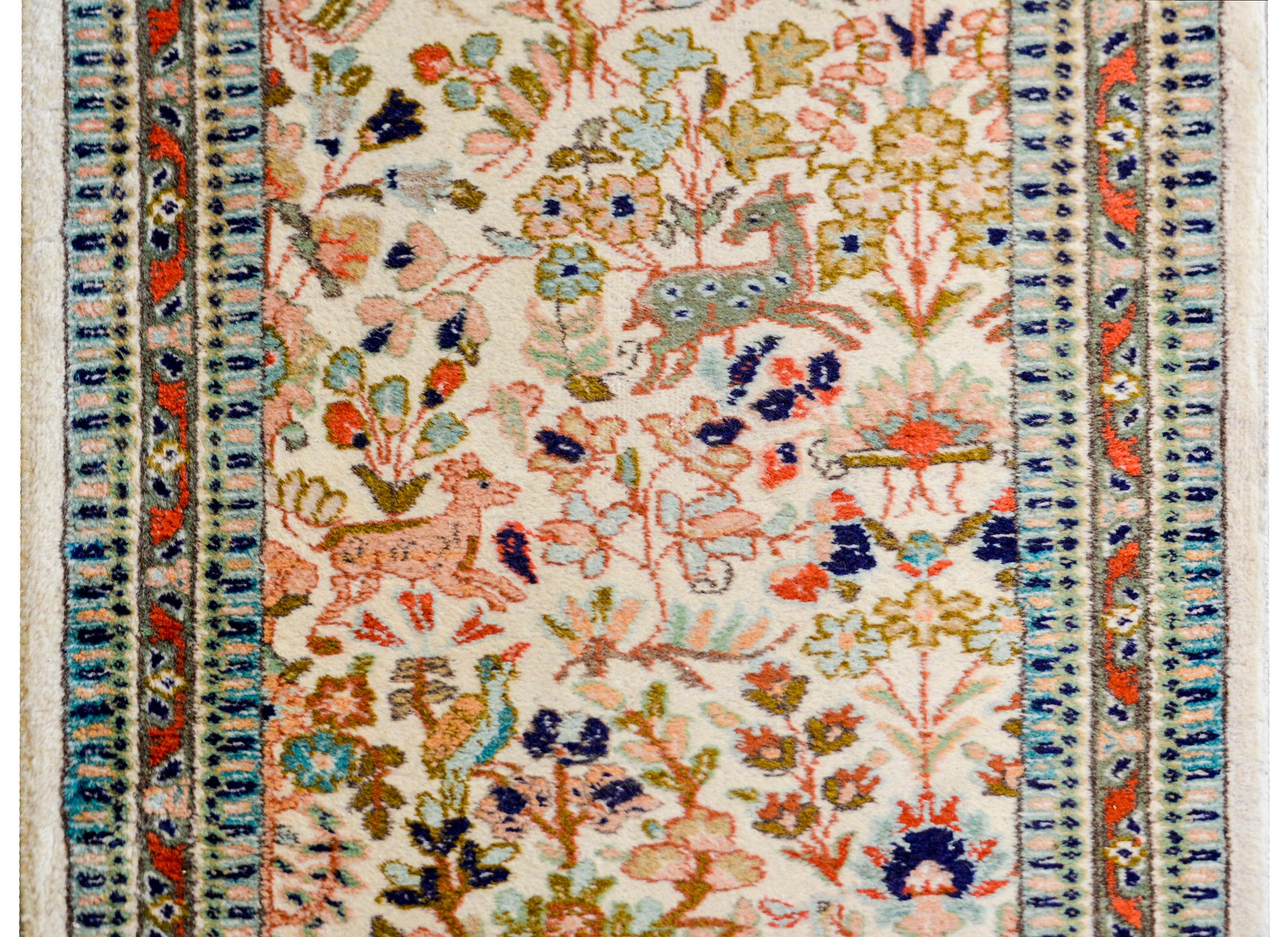A whimsical early 20th century Persian Tabriz runner with a fantastic pattern containing all-over myriad flowers and trees, with myriad animals including deer and birds, woven in pink, green, light and dark indigo, and crimson, on a white wool