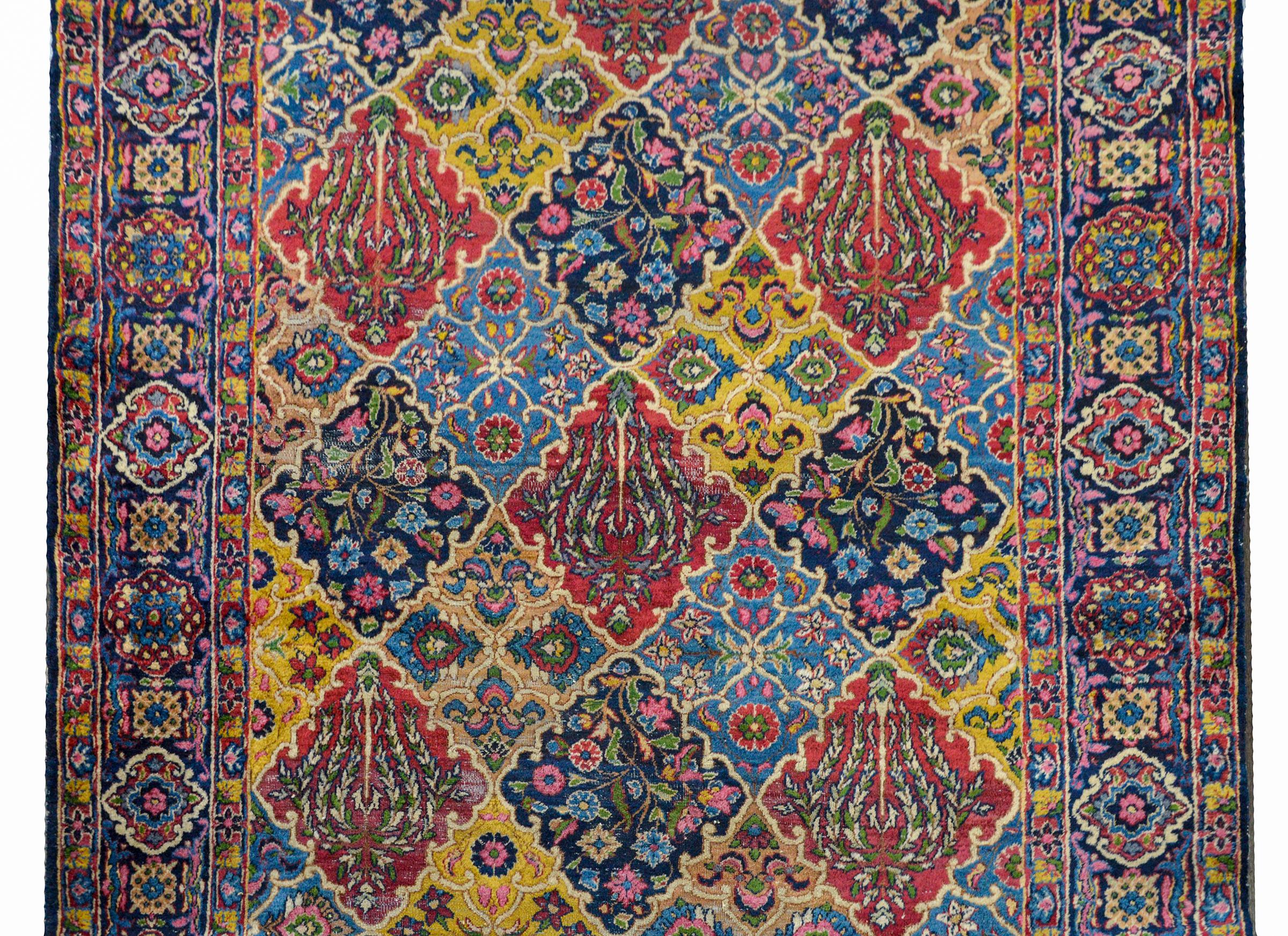 A whimsical early 20th century Persian Yazd runner with a patchwork pattern of myriad flowers and trees-of-life woven in many colors including crimson, light and dark indigo, gold, cream, and pink. The border is unique with a repeated geometric and
