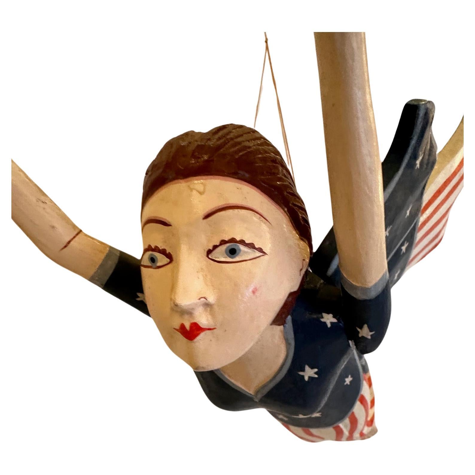 Figure de liberté suspendue en bois sculpté et peint à la main.