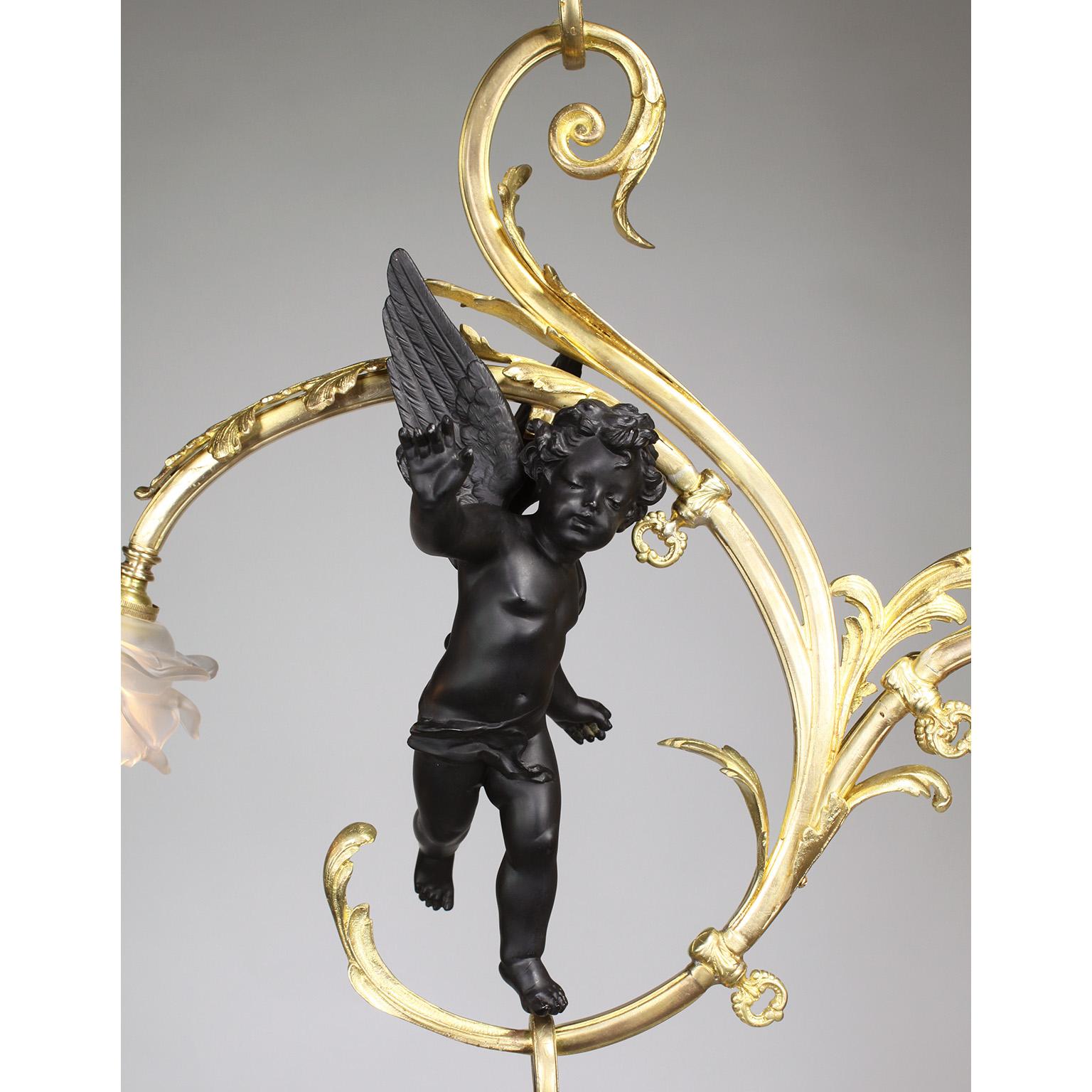 A fine whimsical French Belle Époque gilt and ebonized bronze cherub four-light gasolier pendant chandelier. The scrolled acanthus gilt-bronze frame, with its original gas key-valves surmounted with four frosted glass floral shades and centered with