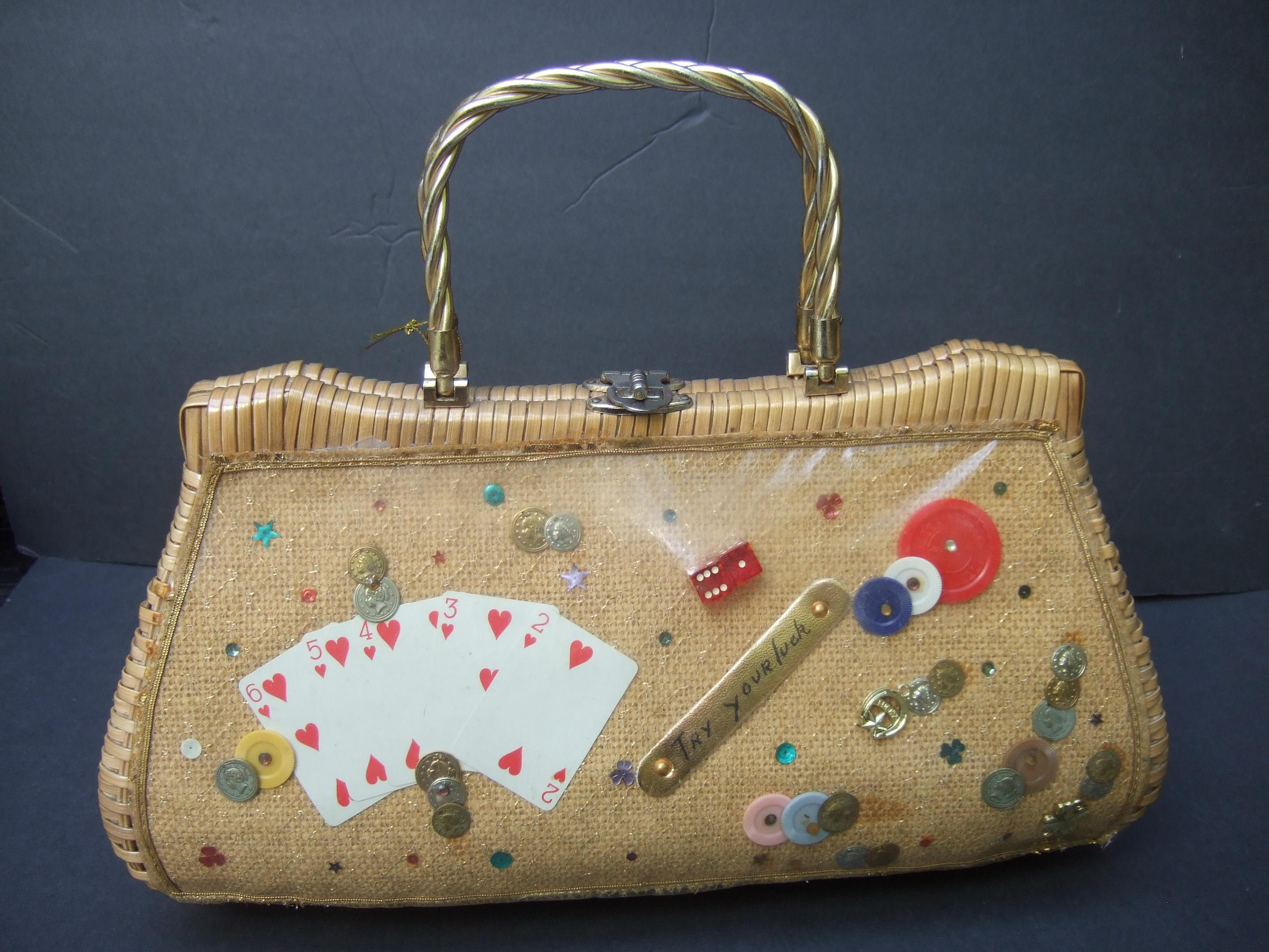 
Skurrile geflochtene Weidenhandtasche mit Retro-Griff um 1960
Die schrullige, lustige Vintage-Handtasche ist mit einer Sammlung von Glücksspiel-Motiven verziert
Artikel; Spielkarten, Würfel, Chips und kleine Metallrepliken von Münzen 

Die