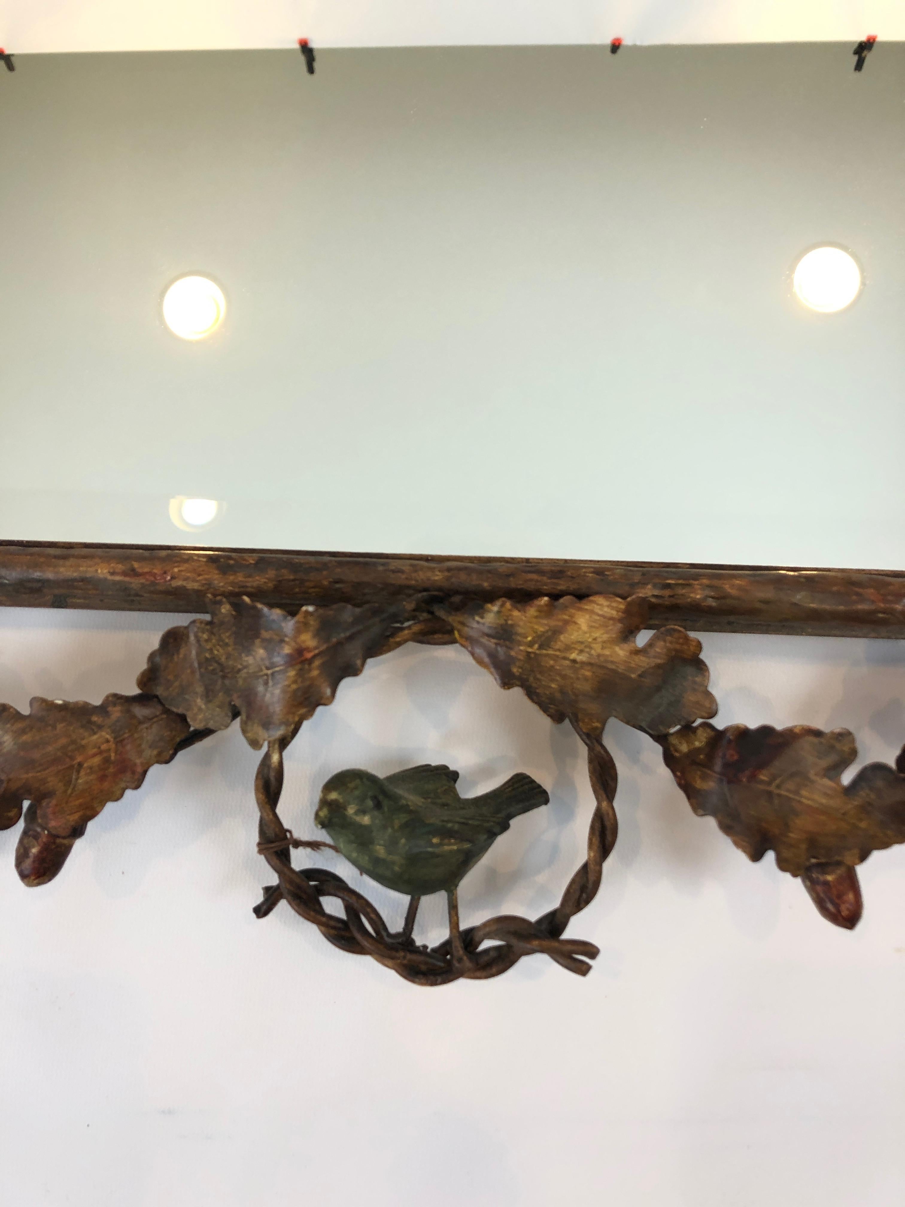 A charming gilt metal faux bois mirror having delightful leaf and acorn decoration and a green patina bird perched on the bottom.