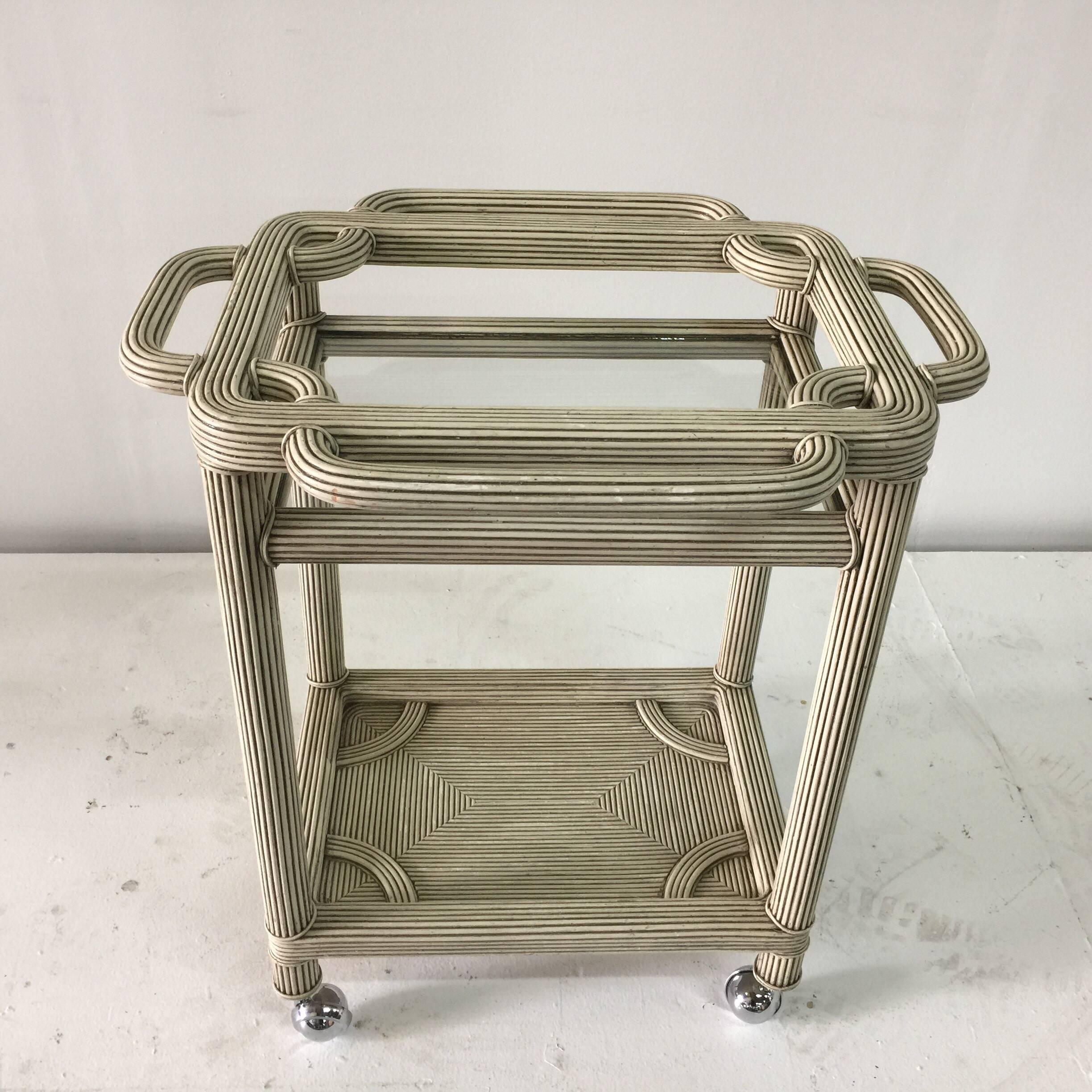 This rolling bar cart is a lovely grey washed natural reed with two tiers. Intricate woven reed in a modern design. Very sturdy with chrome wheels for easy rolling.