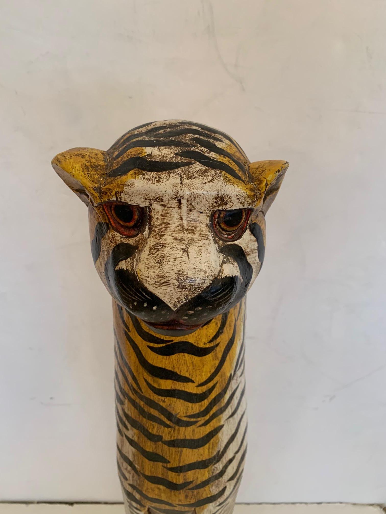 A striking whimsical tall elongated free standing carved wood and hand painted sculpture of a tiger.