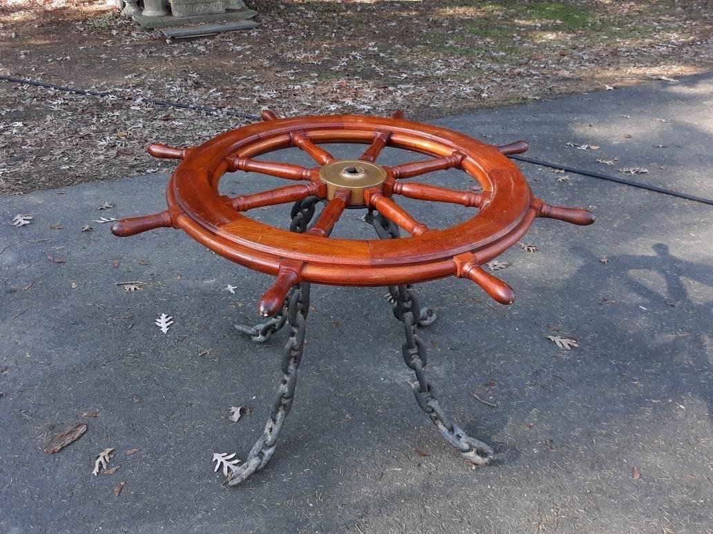 Whimsical one-of-a-kind mahogany ships wheel now as a table. The ships wheel with custom glass top and steel chain welded base. The tabletop from an early to mid-20th Century ships wheel, with a 35-inch glass top supported by a heavy chain link base