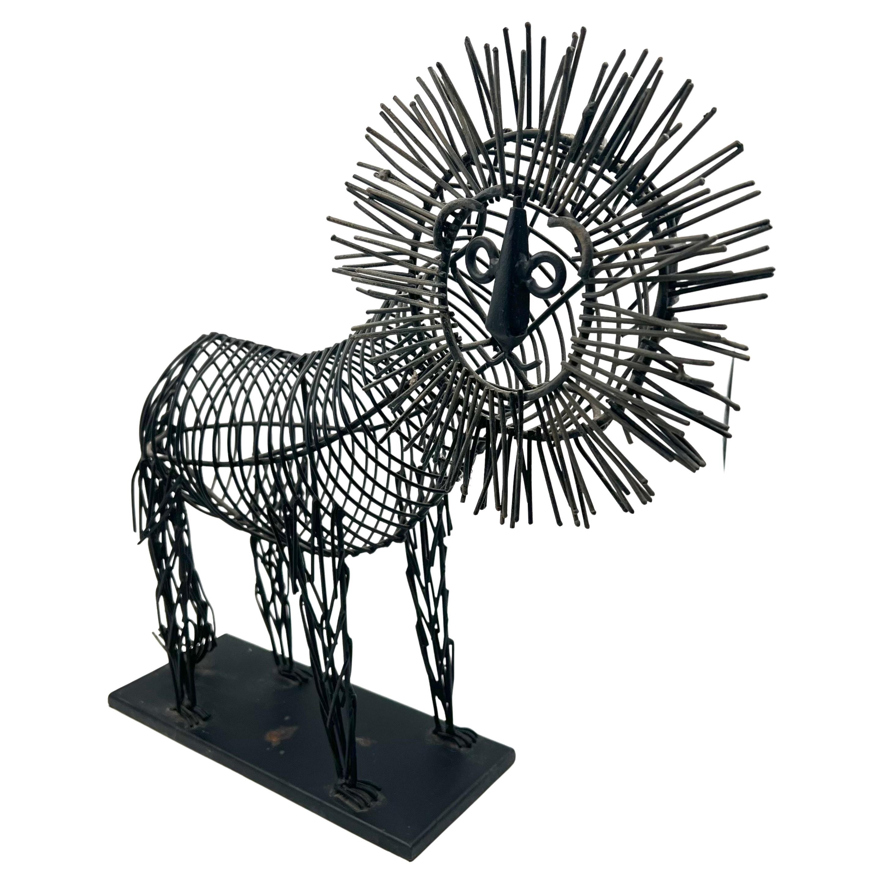 Metal wire sculpture of a lion on a black metal base. The body is black metal wire and the mane is tinted in gold. In the style of C. Jere, circa 1990s.