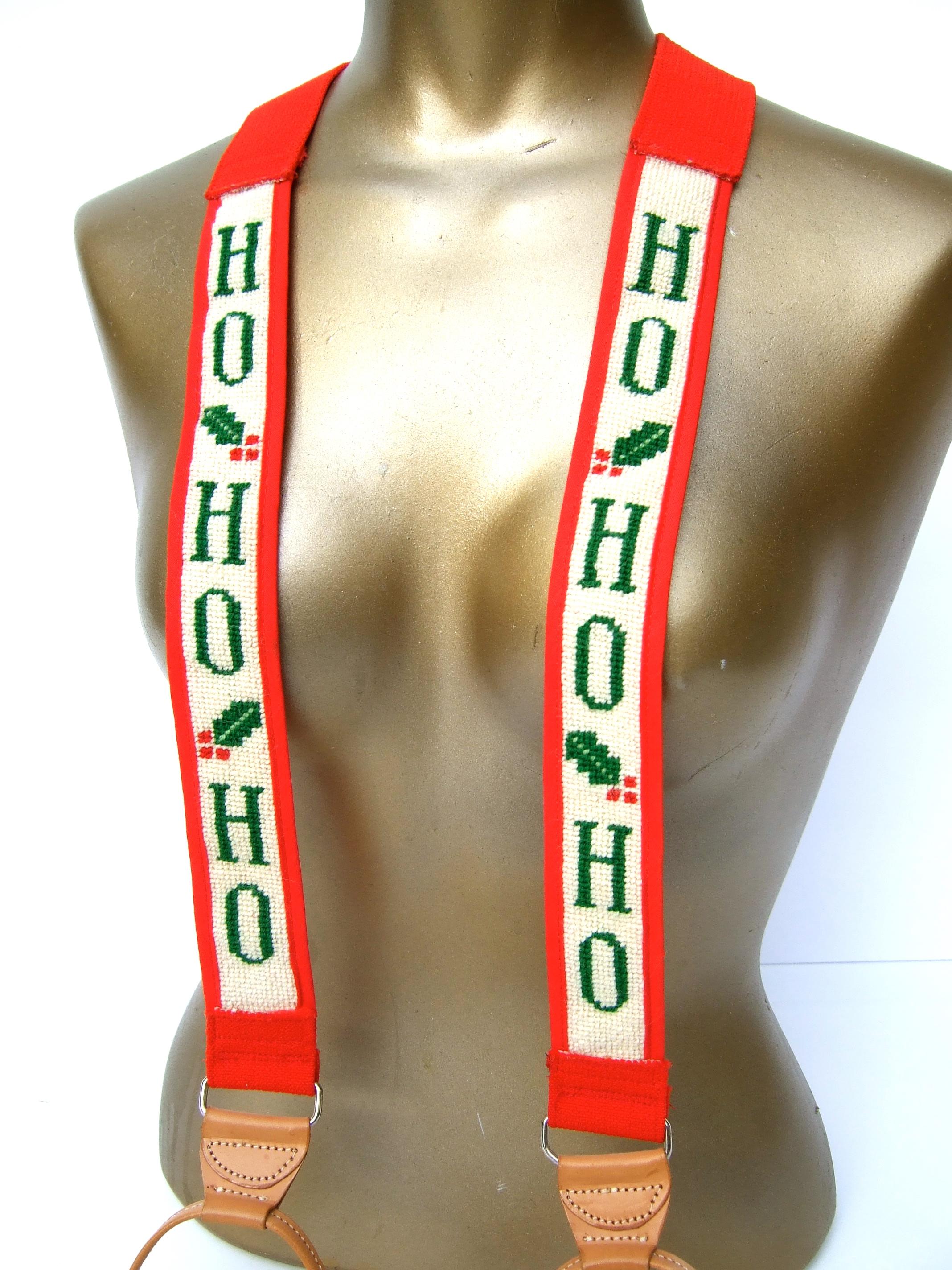 Whimsical needlepoint Christmas themed holiday suspenders c 1980s
The charming hand-stitched unisex suspenders have needlepoint panels designed with mistletoe and the Ho-Ho-Ho jingle 

The solid red section of the suspenders is constructed with