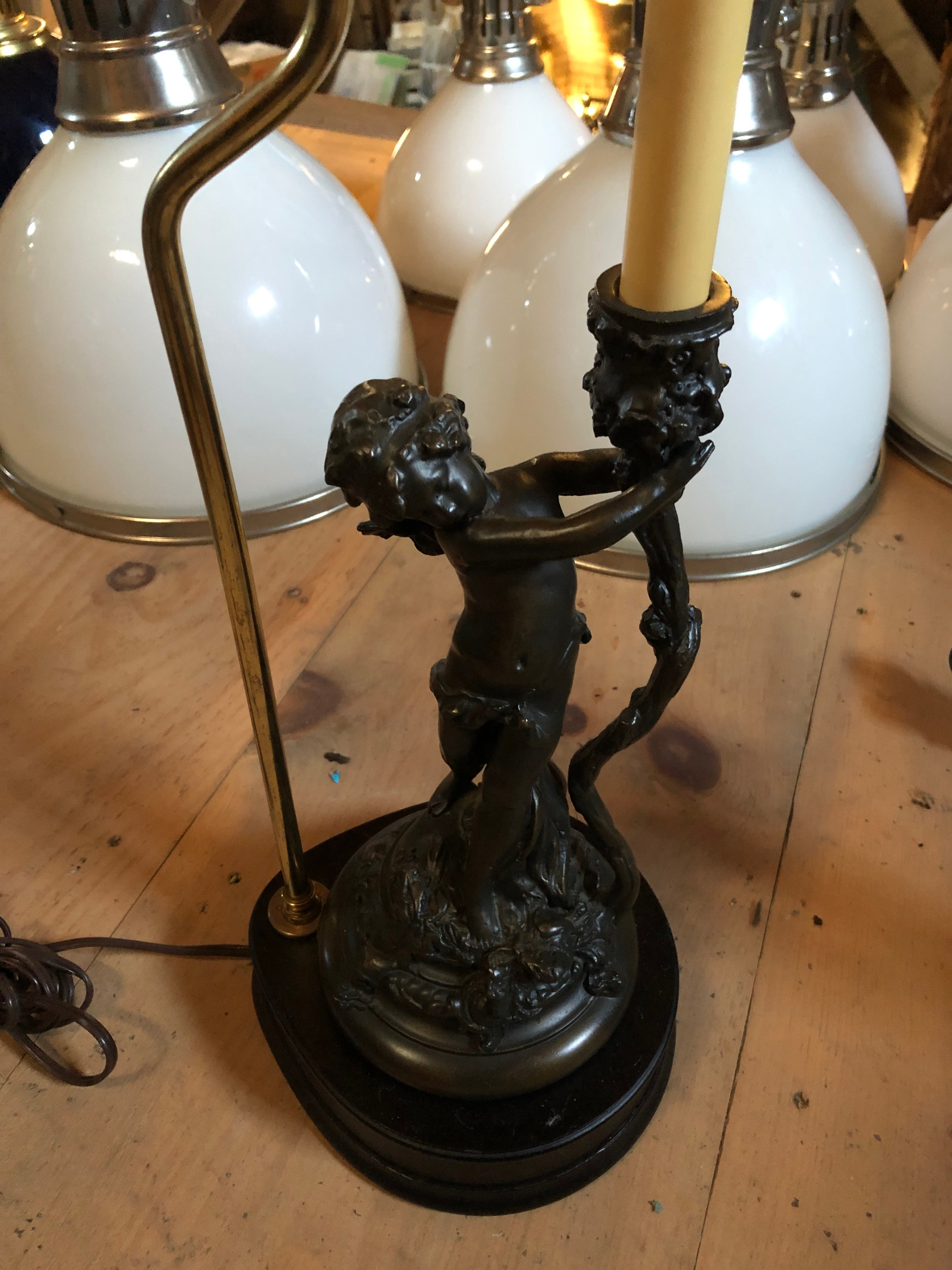 Sweet pair of cherub motif table lamps having single sculptural putti on each wooden base holding a candle form. Metal has a rubbed bronze finish.
No shades included.
While the lamps match, the figures are not set on the stands in exactly the same