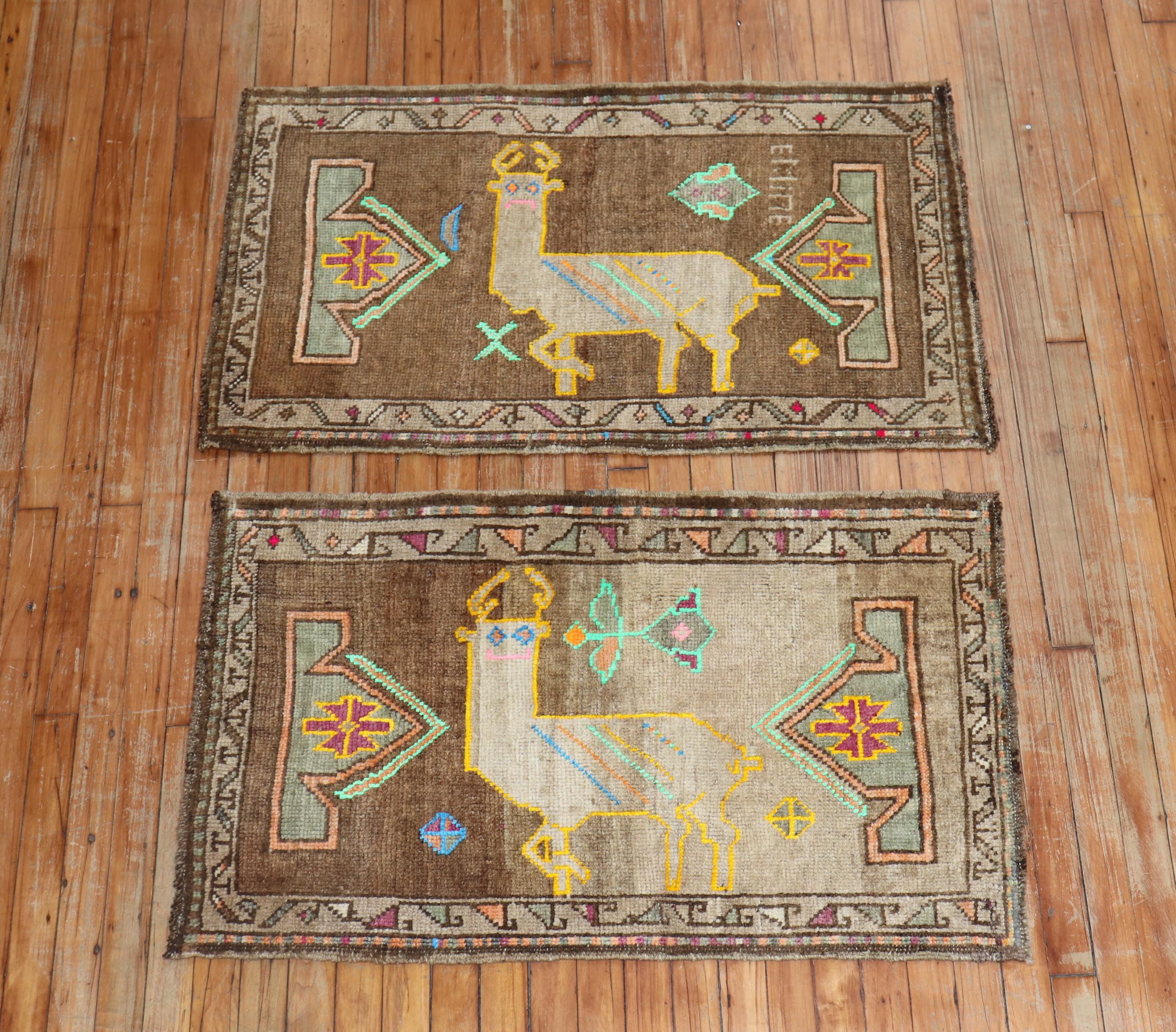 A whimsical pair of one of a kind Turkish rugs depicting colorful goats outlined in yellow, with accents in pistachio and electric blue on a brown ground. The brown ground is faded on of of them 

Measuring 26