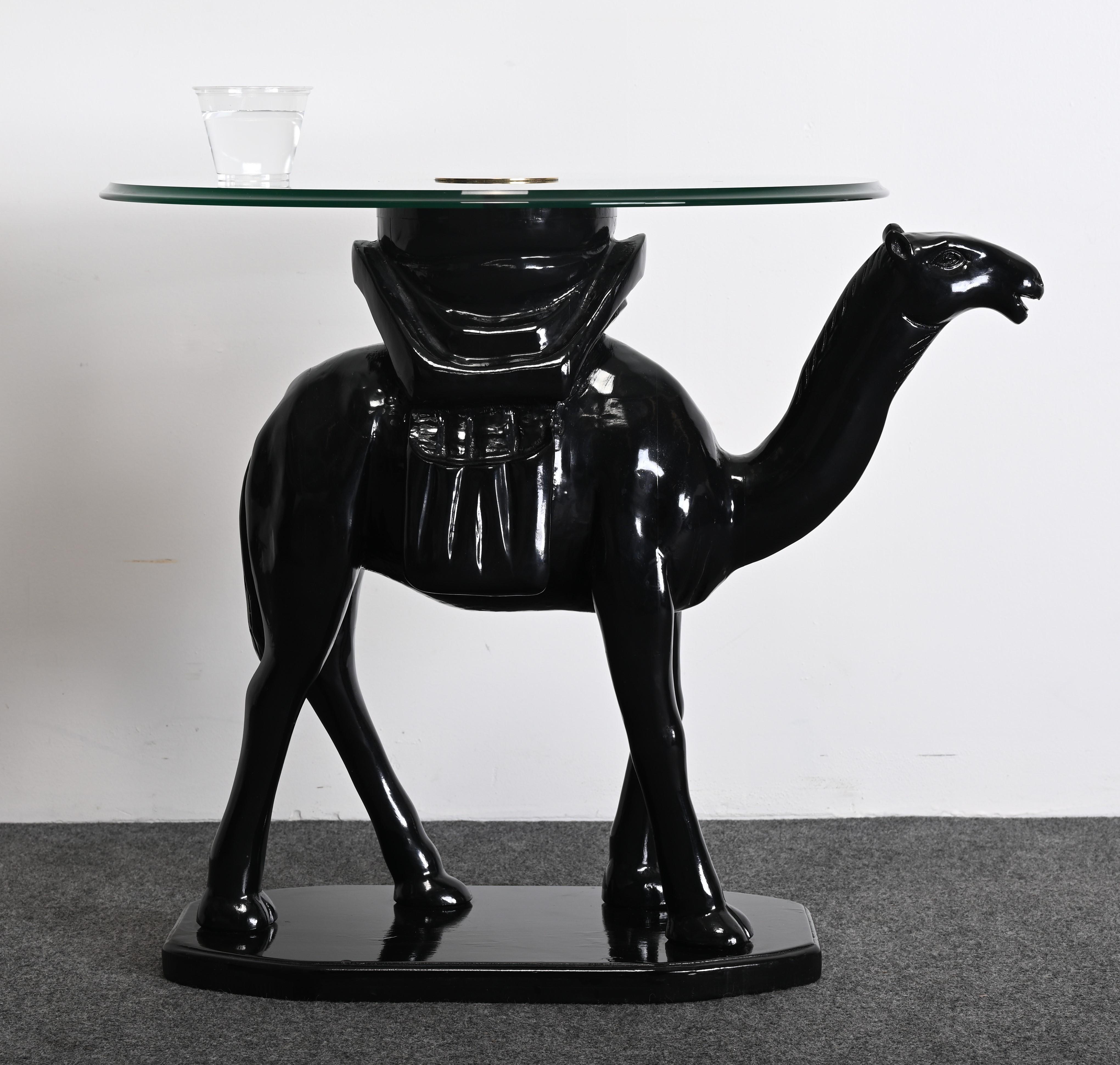 A whimsical Post-Modern side table with a glass top and brass accent. This camel-themed black lacquered side table or cocktail table is made of hand-carved wood. The occasional table came out of a 1980s-designed interior which was accompanied with