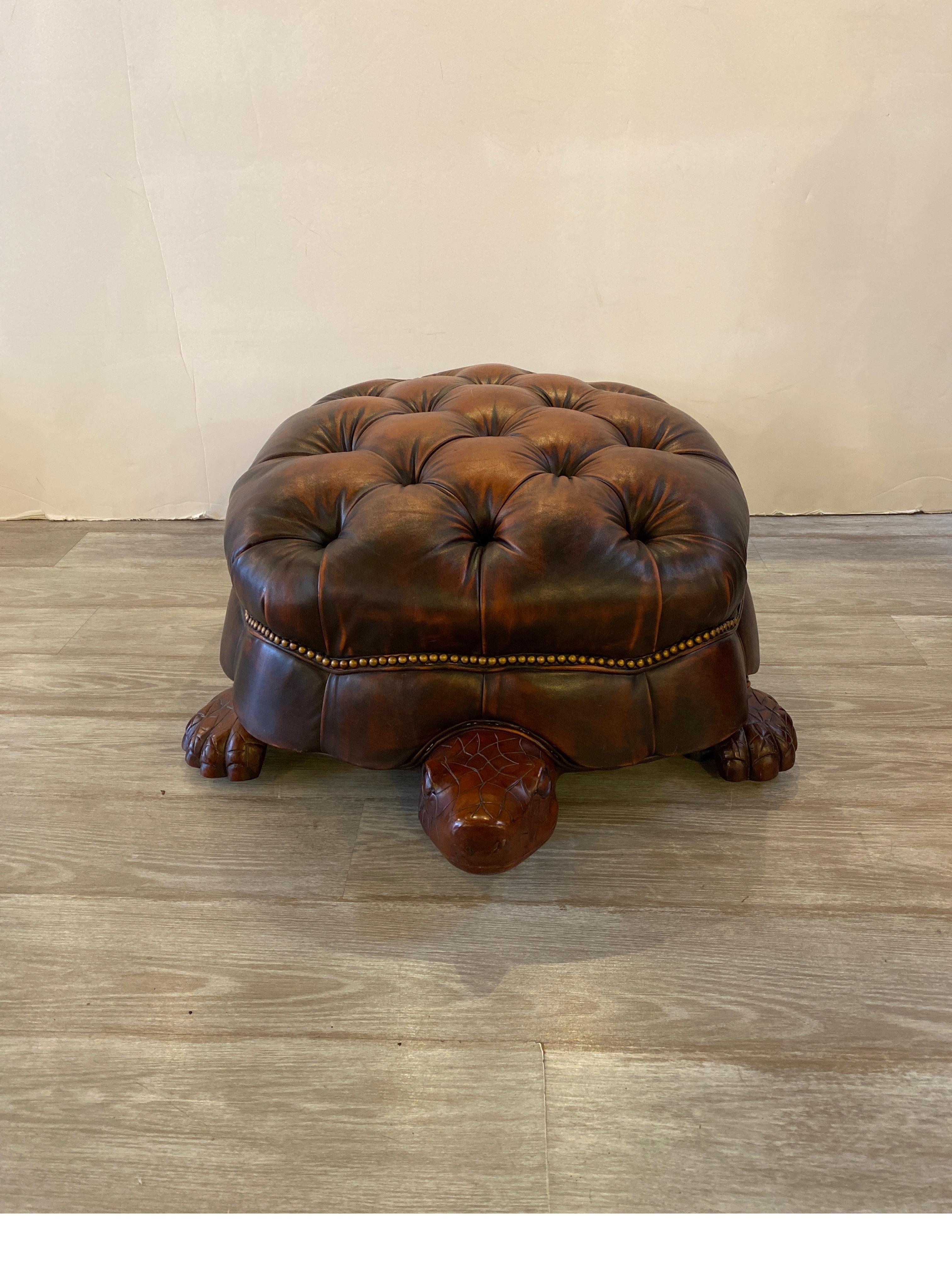 A whimsical turtle form leather tufted oval ottoman with antique brass nail head trim. The antique finish tobacco brown leather with a wood composition turtle shaped base made by Councill. 42 Inches long from nose to tail.