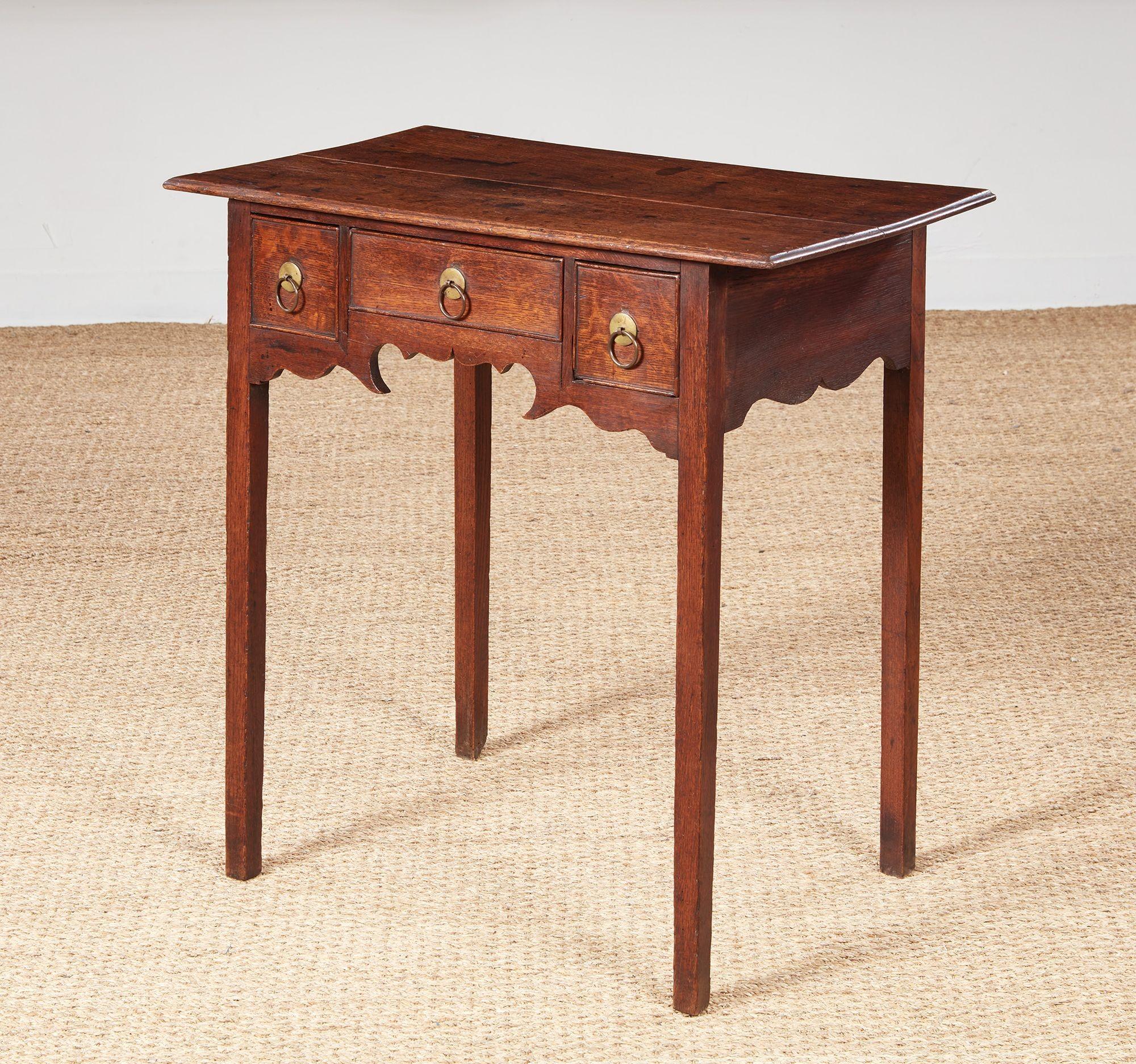 Vernacular George III oak lowboy of unusual design, the thin overhanging molded top over two short and one long drawer with bead molded edges, over whimsically graphic 