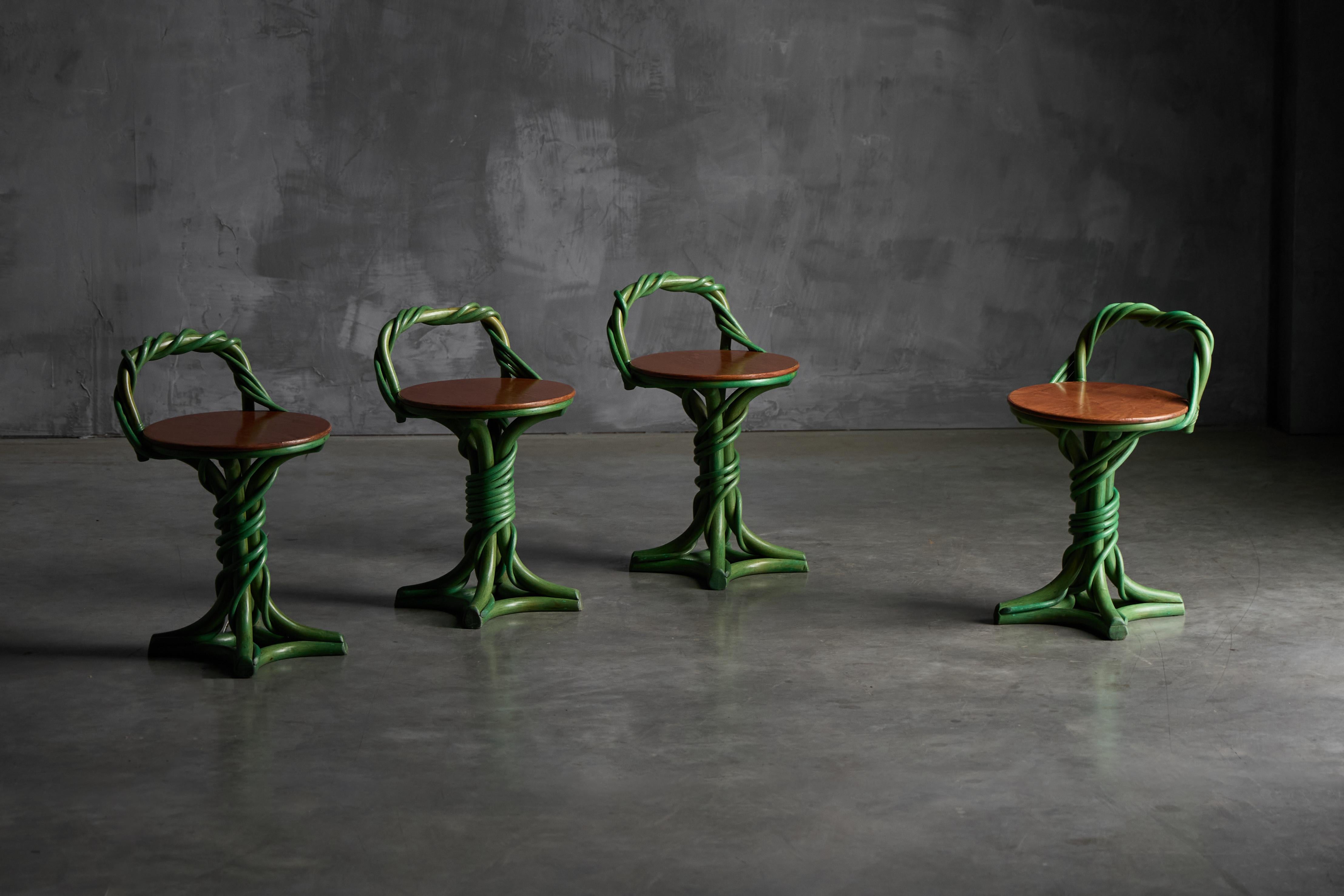 Estos taburetes escultóricos presentan una caprichosa forma inspirada en la vid, con patas verdes entrelazadas y un respaldo curvado que evoca el crecimiento natural. Fabricado con un asiento redondo de madera ricamente teñida, la base se asemeja a