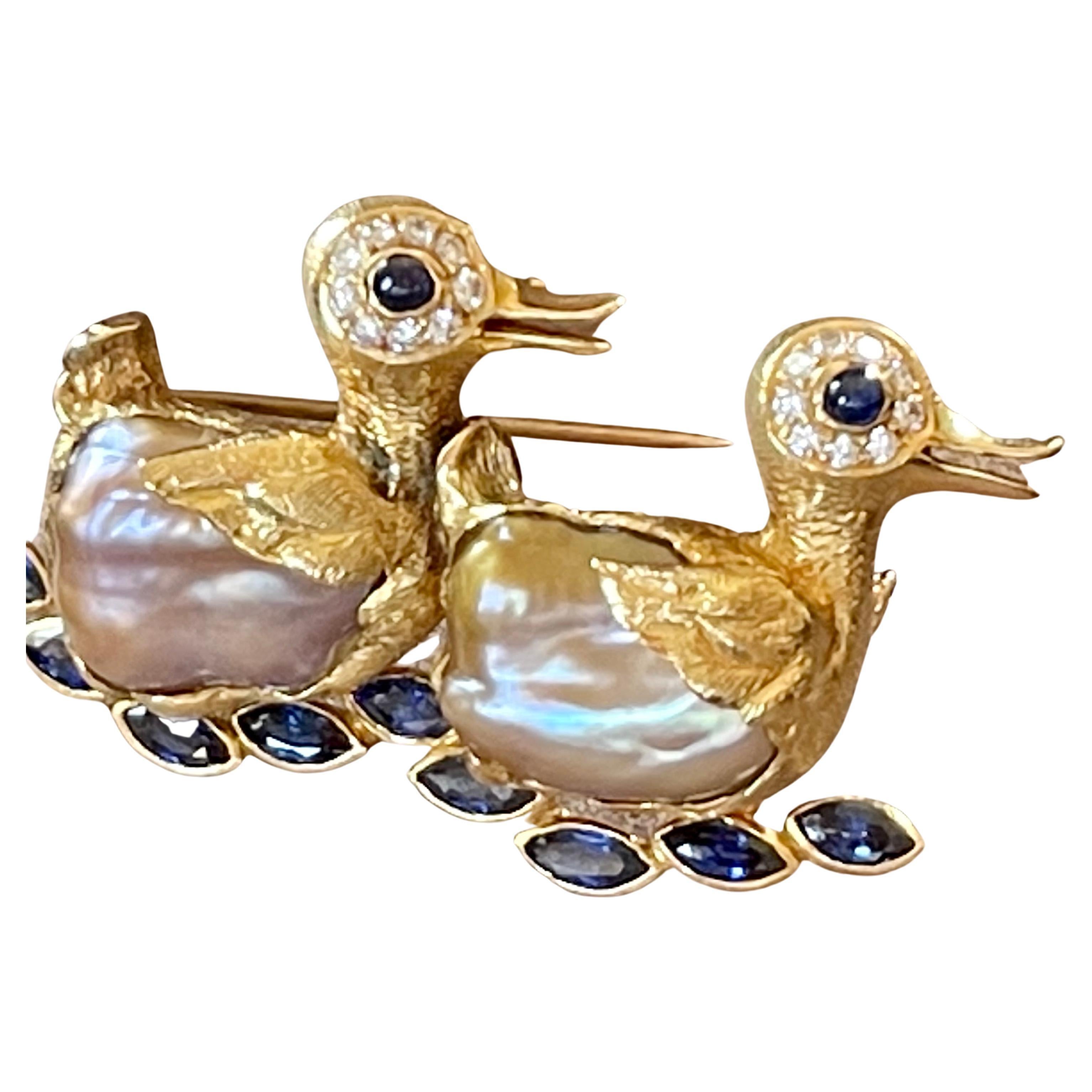 An adorable 18 K yellow Gold Duck brooch featuring 2 baroque freshwater perals that build the duck's body. 9 marquise shape blue Sapphires weighing approximately 2.50 ct, 4 Sapphire Cabochons for the eyes and 18 tiny round brilliant cut Diamonds