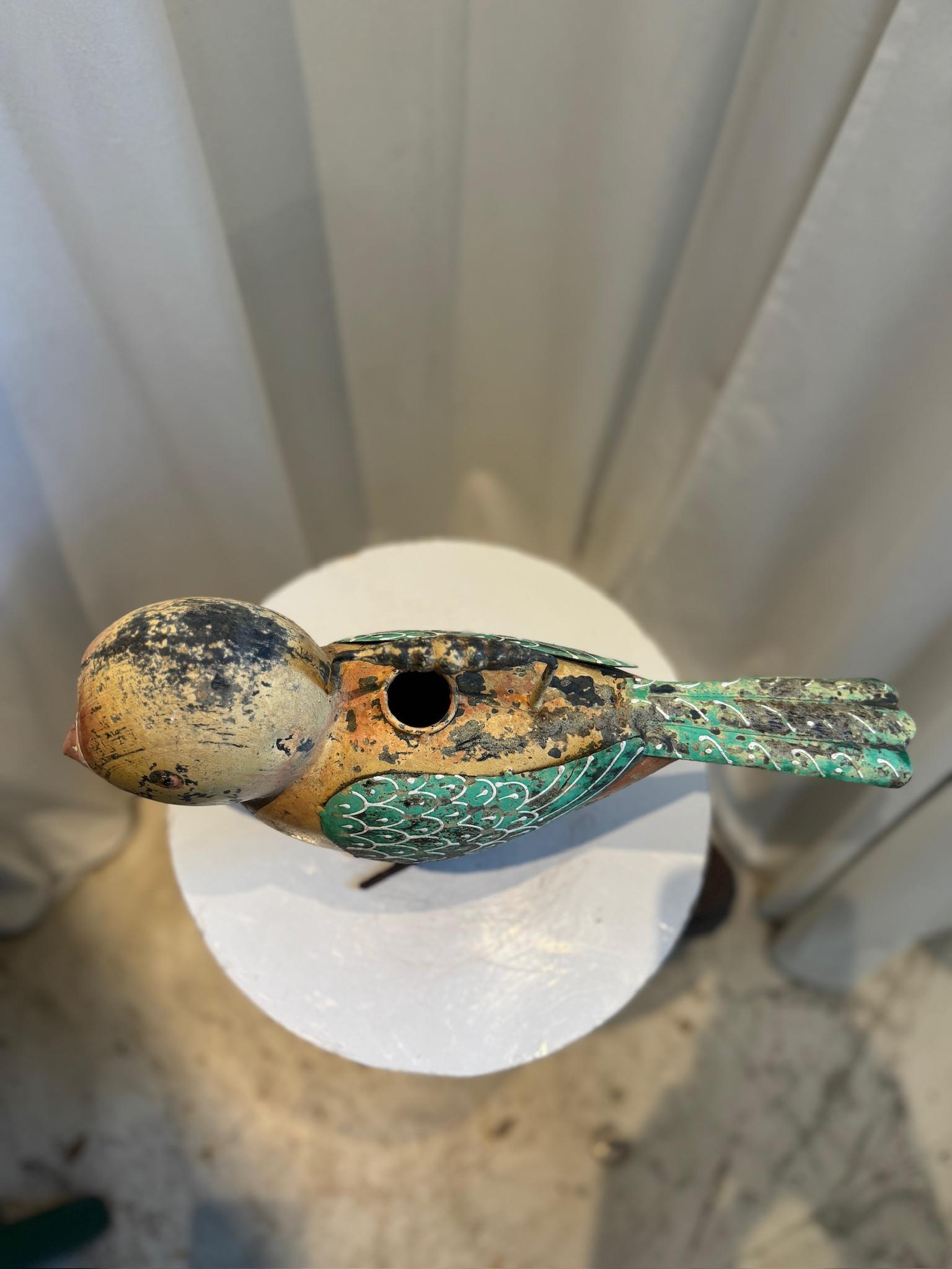 Infondi un fascino giocoso al tuo giardino o al tuo spazio interno con questo stravagante annaffiatoio vintage a forma di uccello. Realizzato artigianalmente in metallo e dipinto a mano in una ricca tavolozza di giallo ocra, verde foglia e arancione