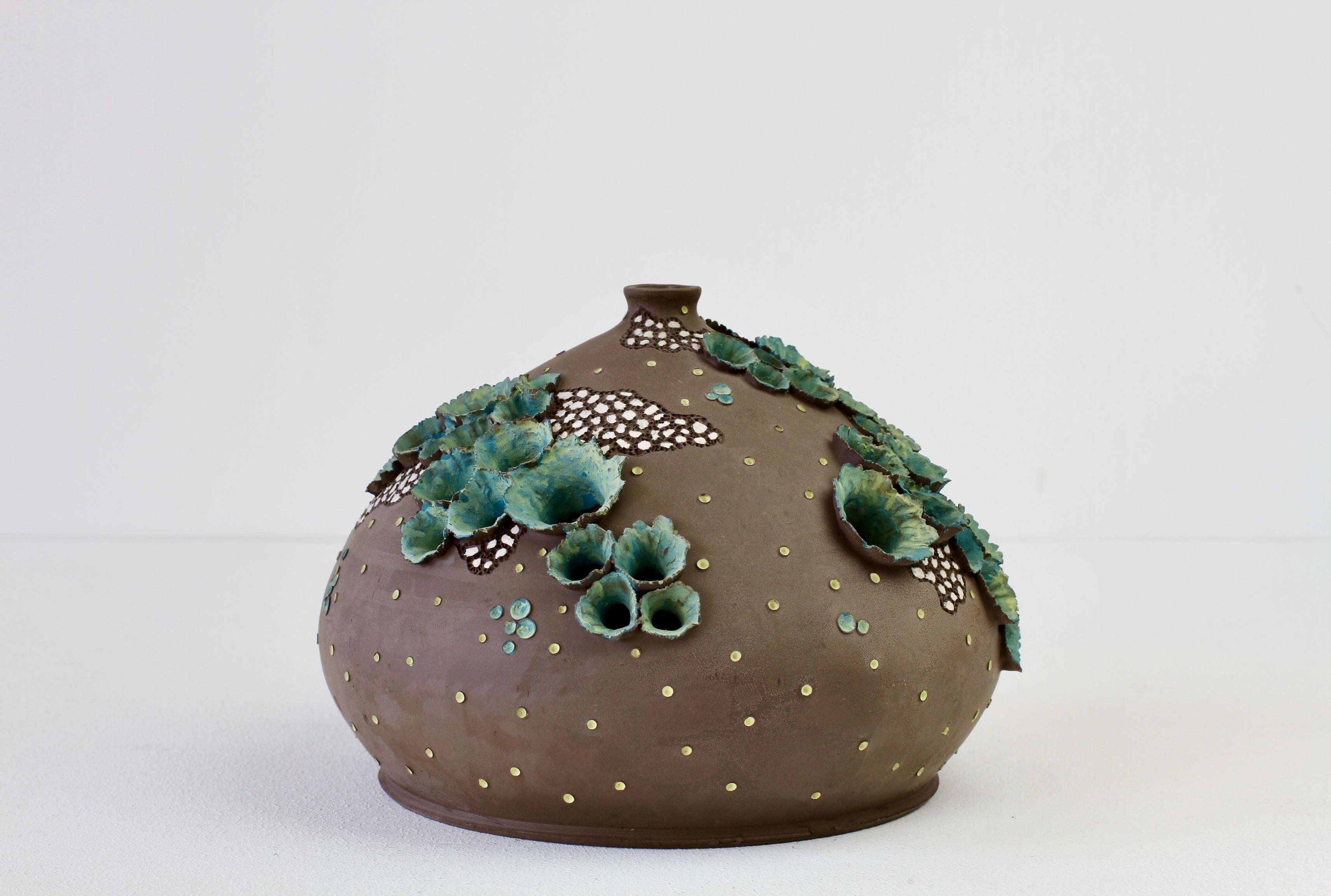 Whimsical, interesting and intriguing piece of studio art pottery vase or vessel with holes and 'flower' / 'plant like' details applied - also made of clay. The piece is signed by the artist but we have not yet been able to identify them. Most