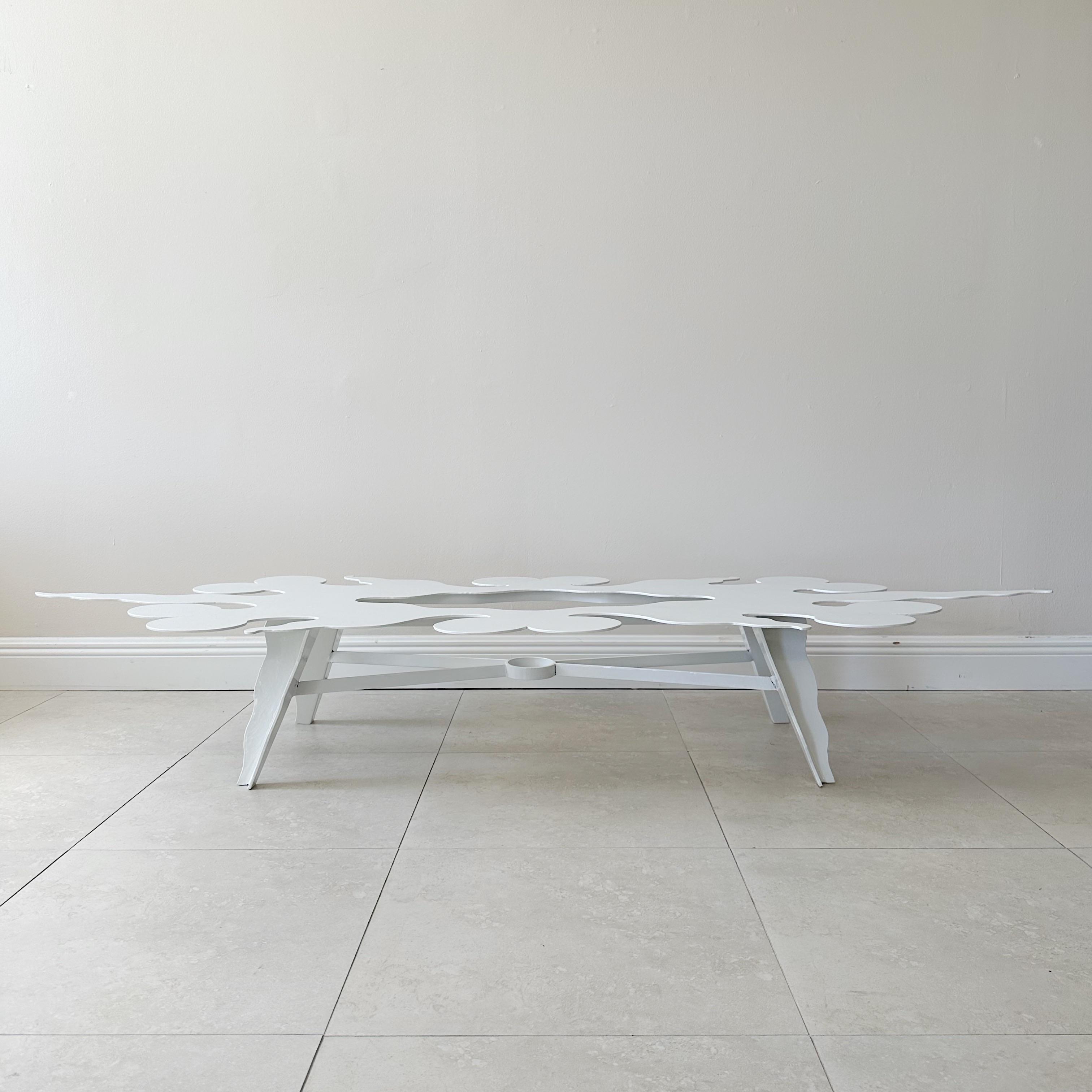 This vintage coffee table is a stunning addition to any home decor with its unique cutout design and fresh Palm Beach White powder coating. The table features a sturdy steel construction with a four-legged x-stretcher design, providing both