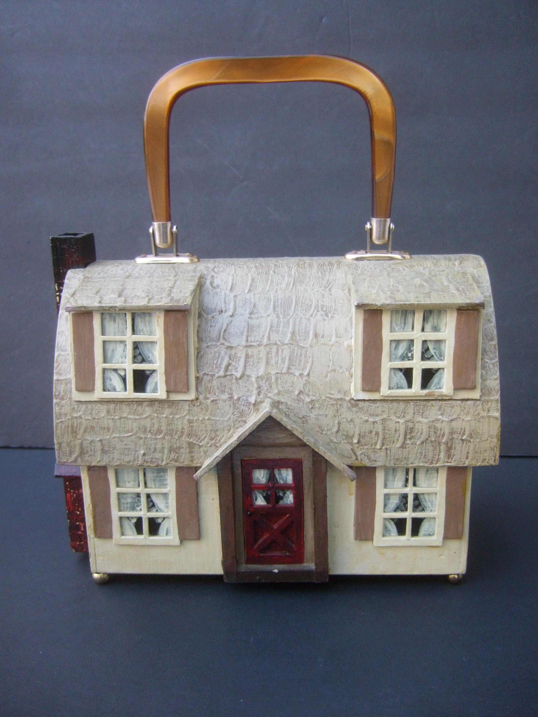 Whimsical wood enamel handmade artisan house design handbag c 1970s
The unique quirky vintage box purse is designed with a charming cottage style home
Decorated with a textured enamel roof that emulates shingles; accented with handpainted enamel
