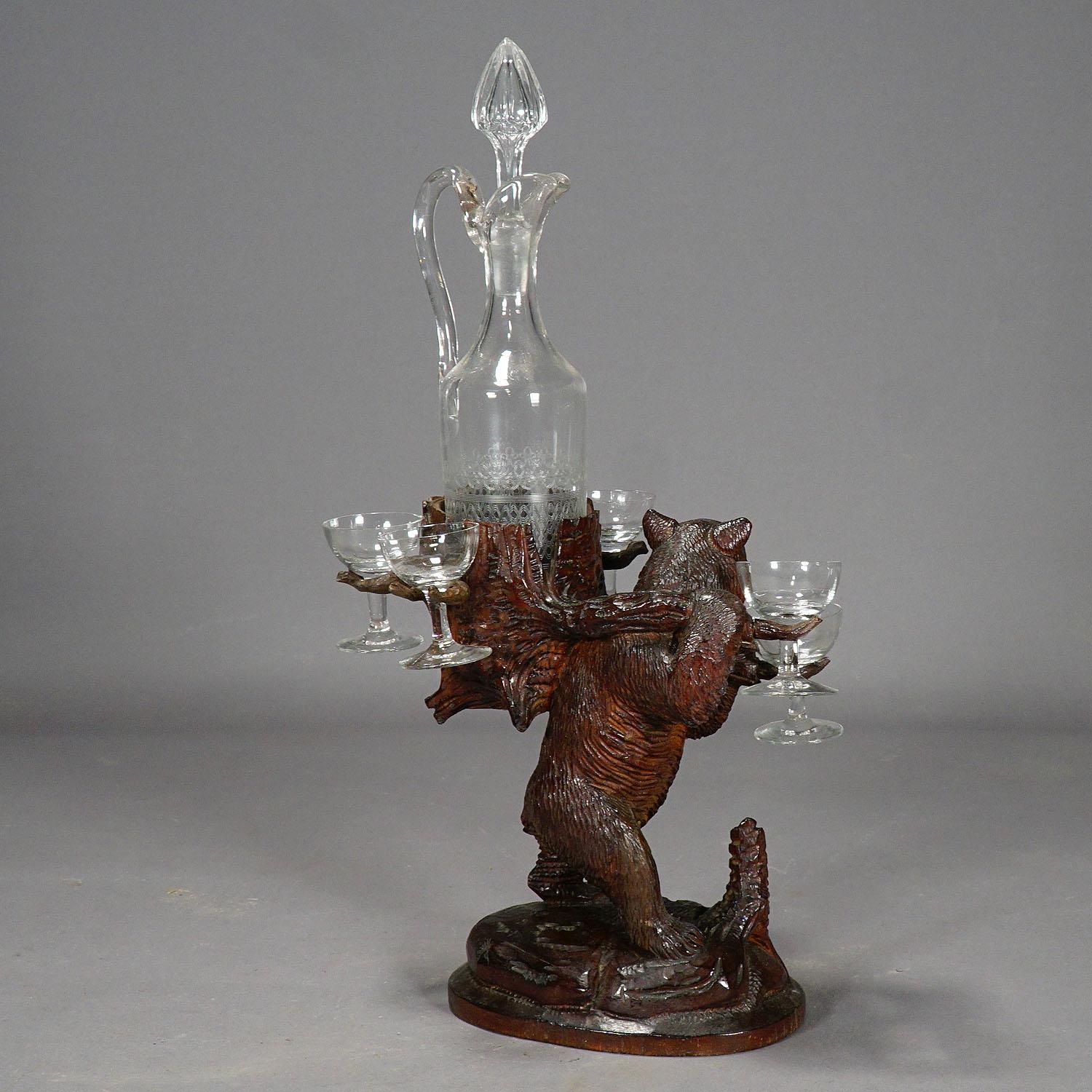 Item e6177
A carved linden wood decanter / liqueur Stand modelled as a hiking bear with basket on his back. with engraved crystal decanter and six shot glasses. executed circa 1900, swiss brienz.

Measures: Width 9.45