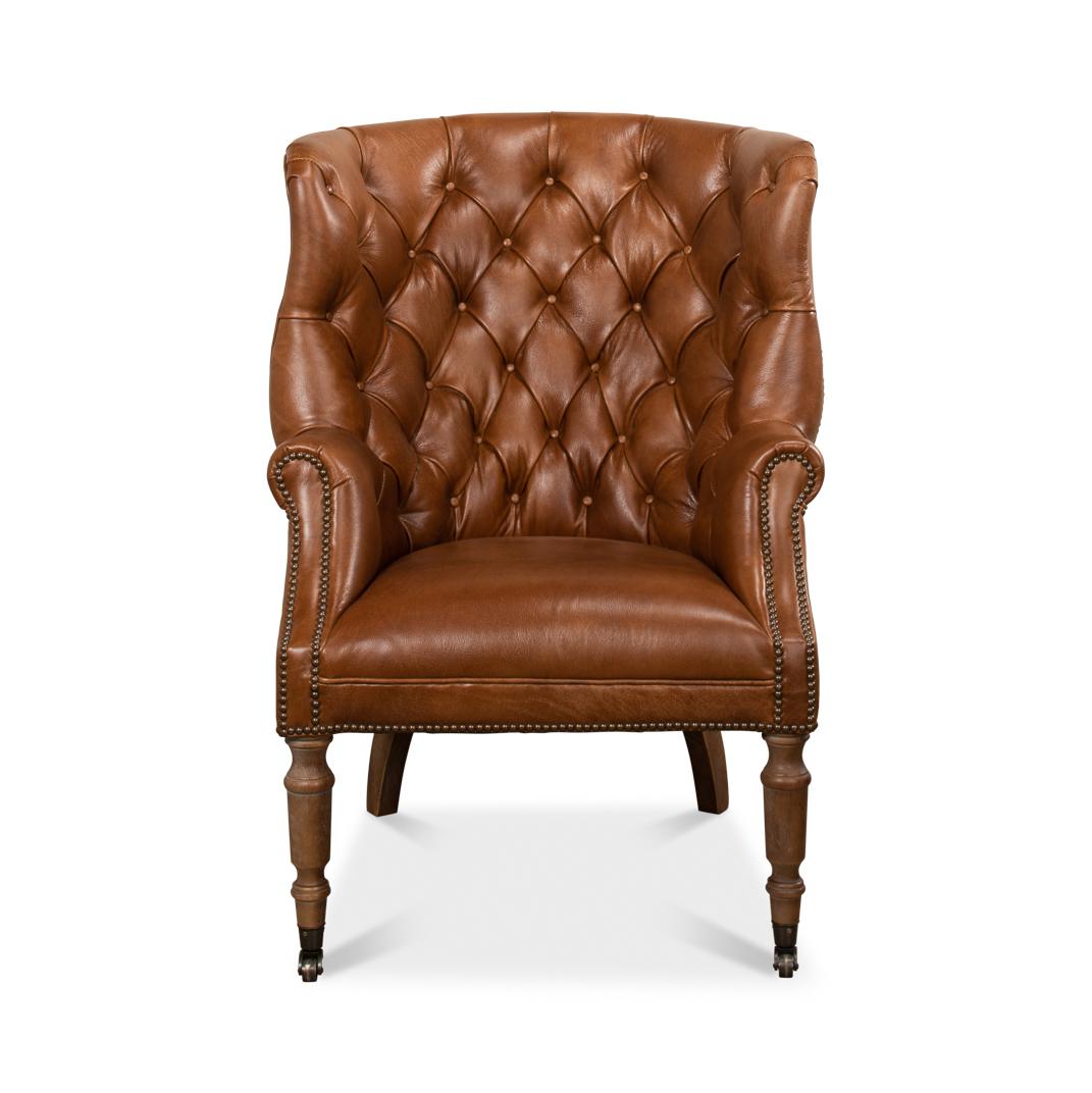 A wonderful George III style barrel back wingchair with top-grain Whiskey Brown Leather, a tufted upholstery barrel backrest with winged sides, rolled arms and a padded seat. Finished with brass nailhead trim and raised on cerused turned front legs