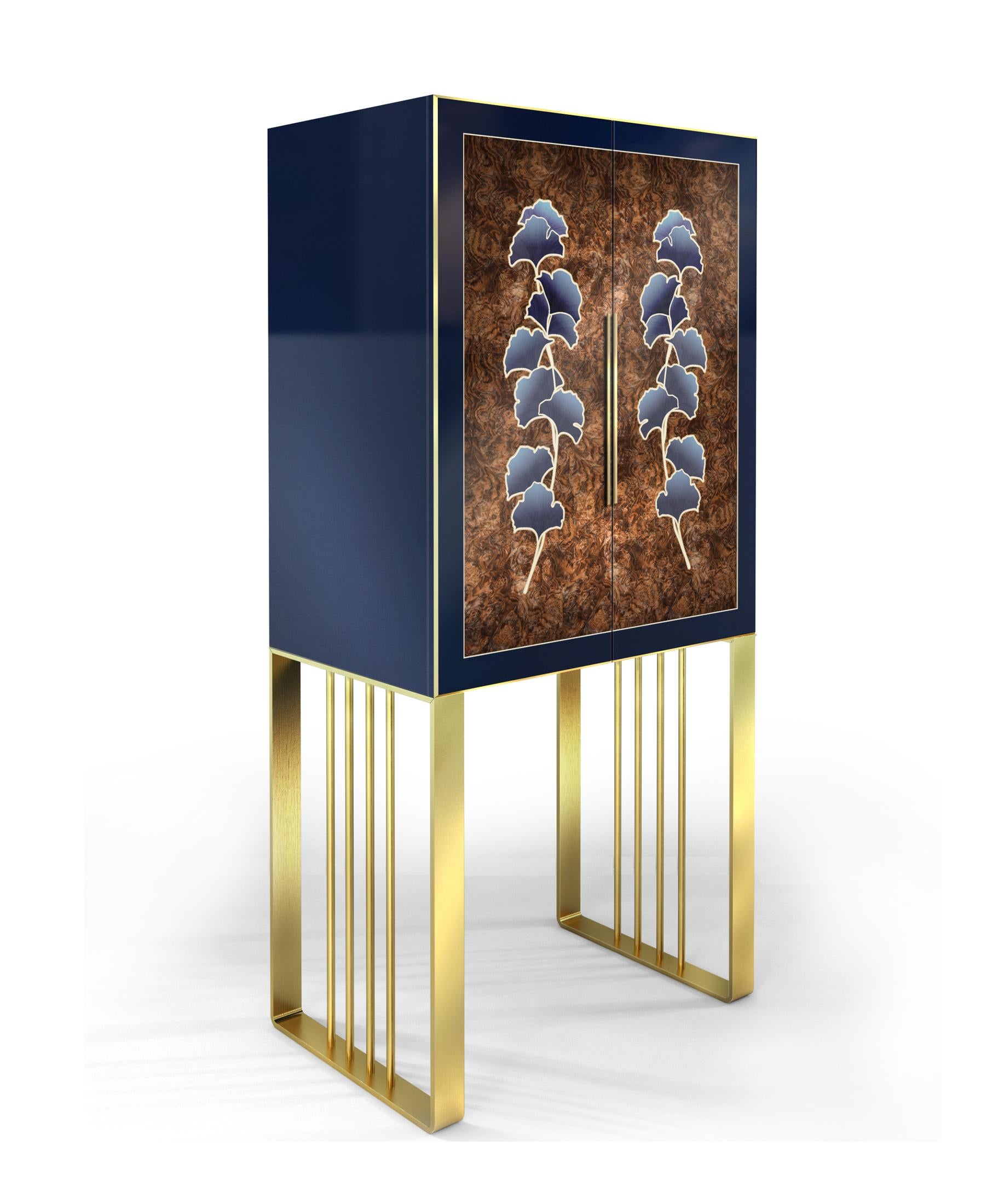 This elegant drinks cabinet is handcrafted in satin navy blue lacquer finish, rich in texture burl walnut and supported with intricate brushed brass legs. The hand-dyed English oak marquetry creates a Ginkgo leaf motif which symbolizes hope and