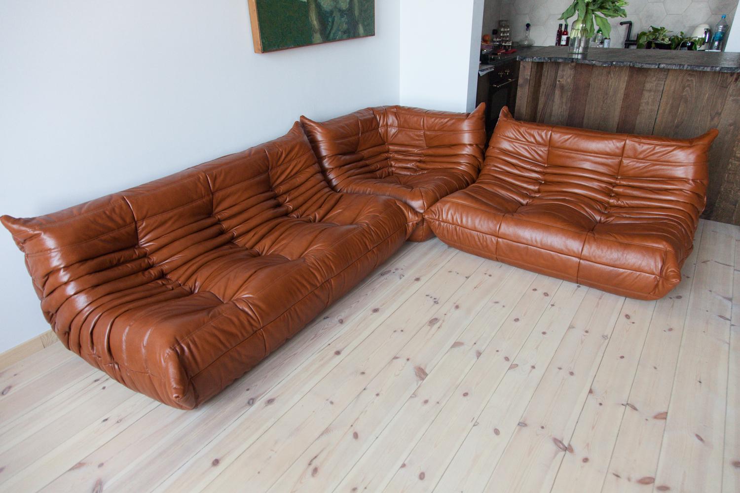 This Togo living room set was designed by Michel Ducaroy in 1973 and was manufactured by Ligne Roset in France. It has been reupholstered in high quality whiskey leather and is made up of the following pieces, each with the original Ligne Roset logo