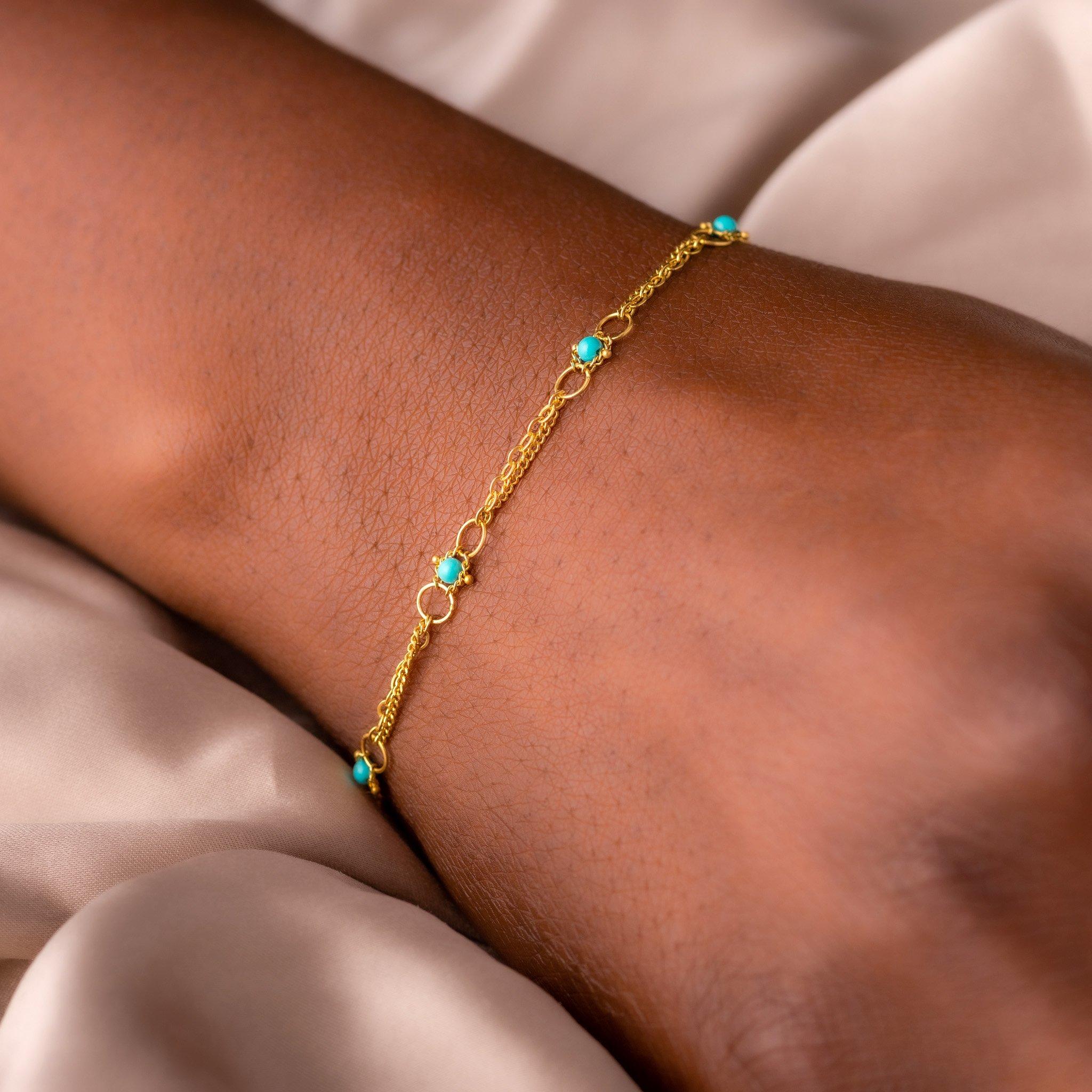 Delicate 18K yellow gold chain encircles the wrist like strands of sunlight, punctuated at intervals by round Turquoise beads of a perfect robin’s egg blue. The links of the meticulously hand-woven chains form tiny, intricate patterns that draw the