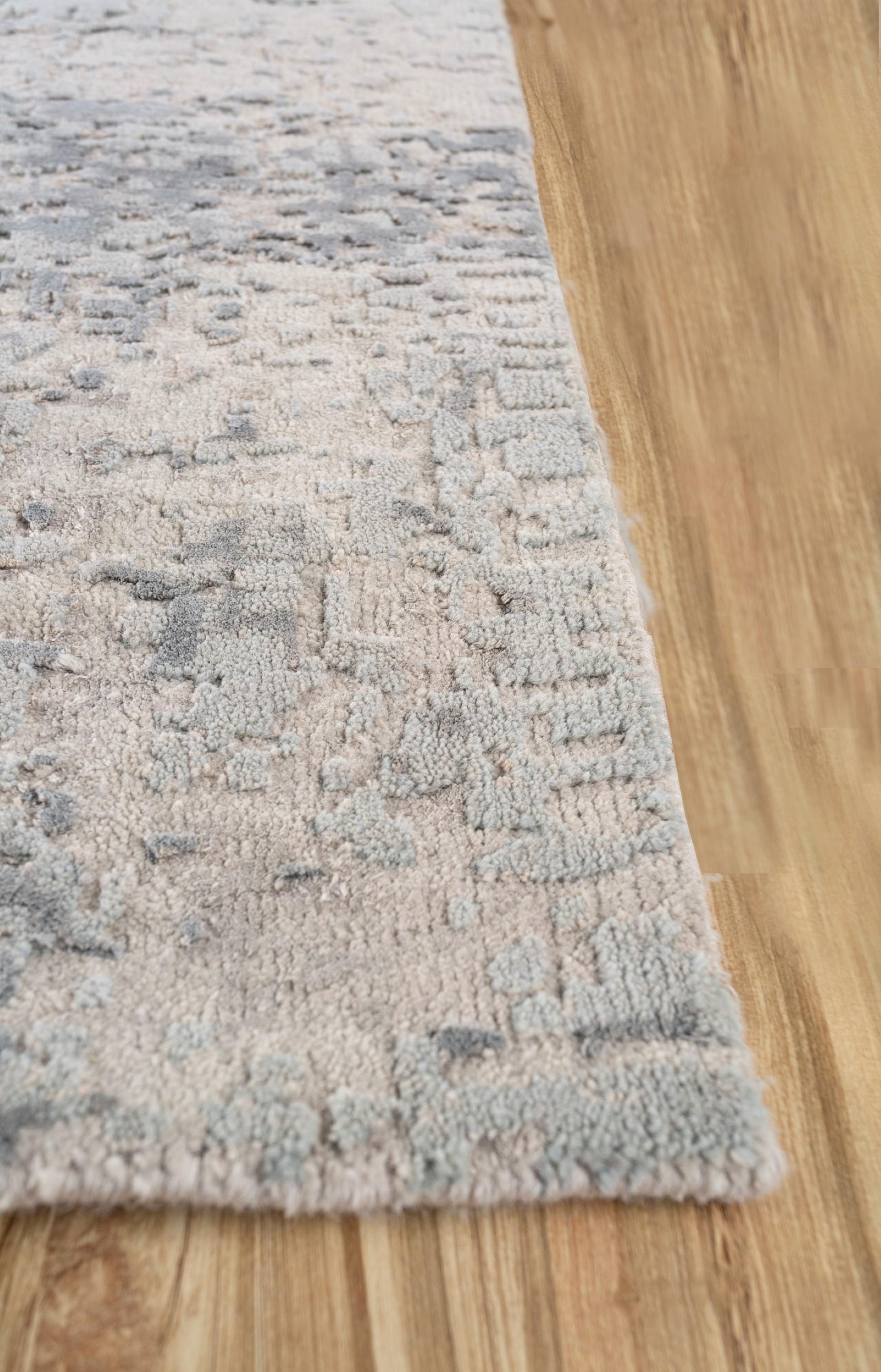 Lassen Sie sich von der Kunstfertigkeit unseres handgeknüpften Teppichs verzaubern, einer Verschmelzung von antikem Weiß und Pastellblau in einem modernen Design. Inspiriert von beobachteten Kerzenlichtmustern, erzählt dieser Teppich durch